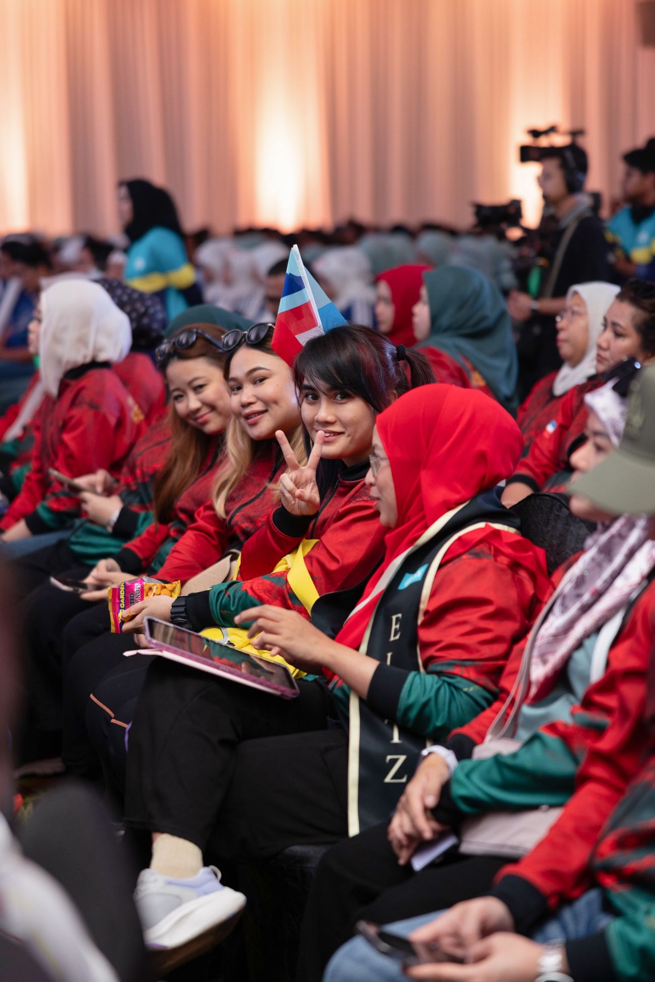 Attendees in red jackets smile and pose with peace signs at BSN corporate conference event.
