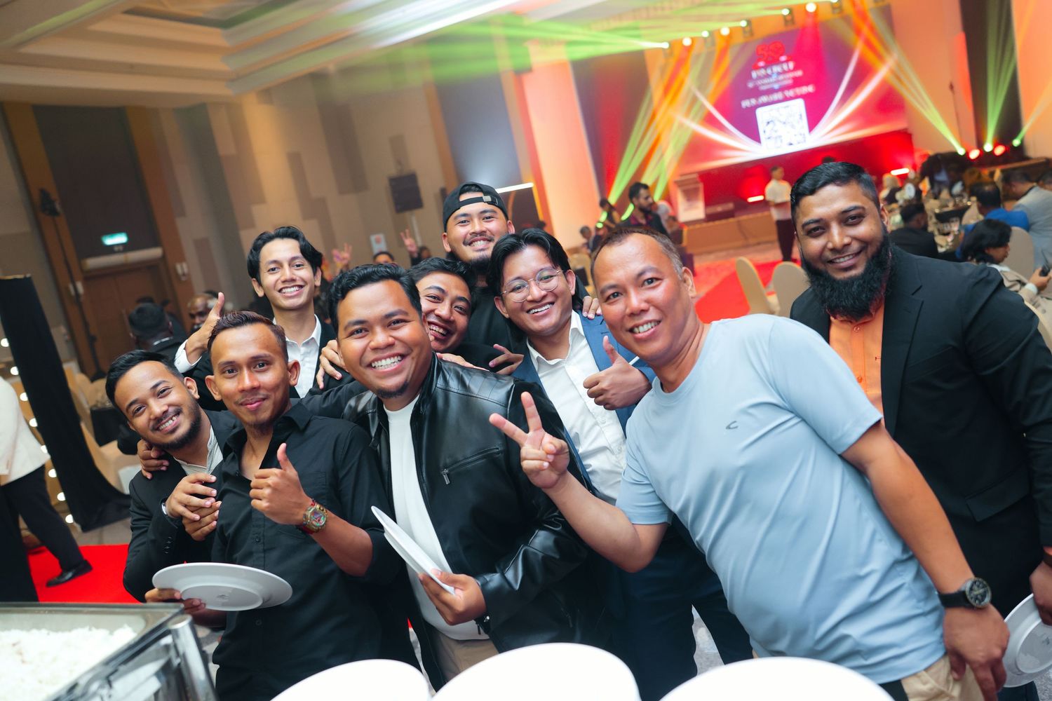 Group of cheerful young men smiling and posing together at a vibrant evening entertainment event.