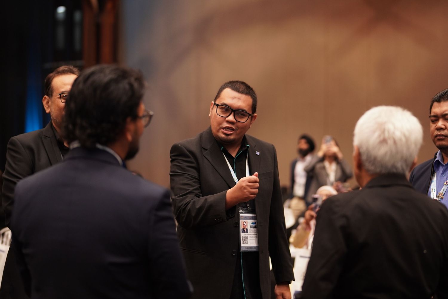 Business professionals engaged in a networking conversation at a conference event in a formal setting.