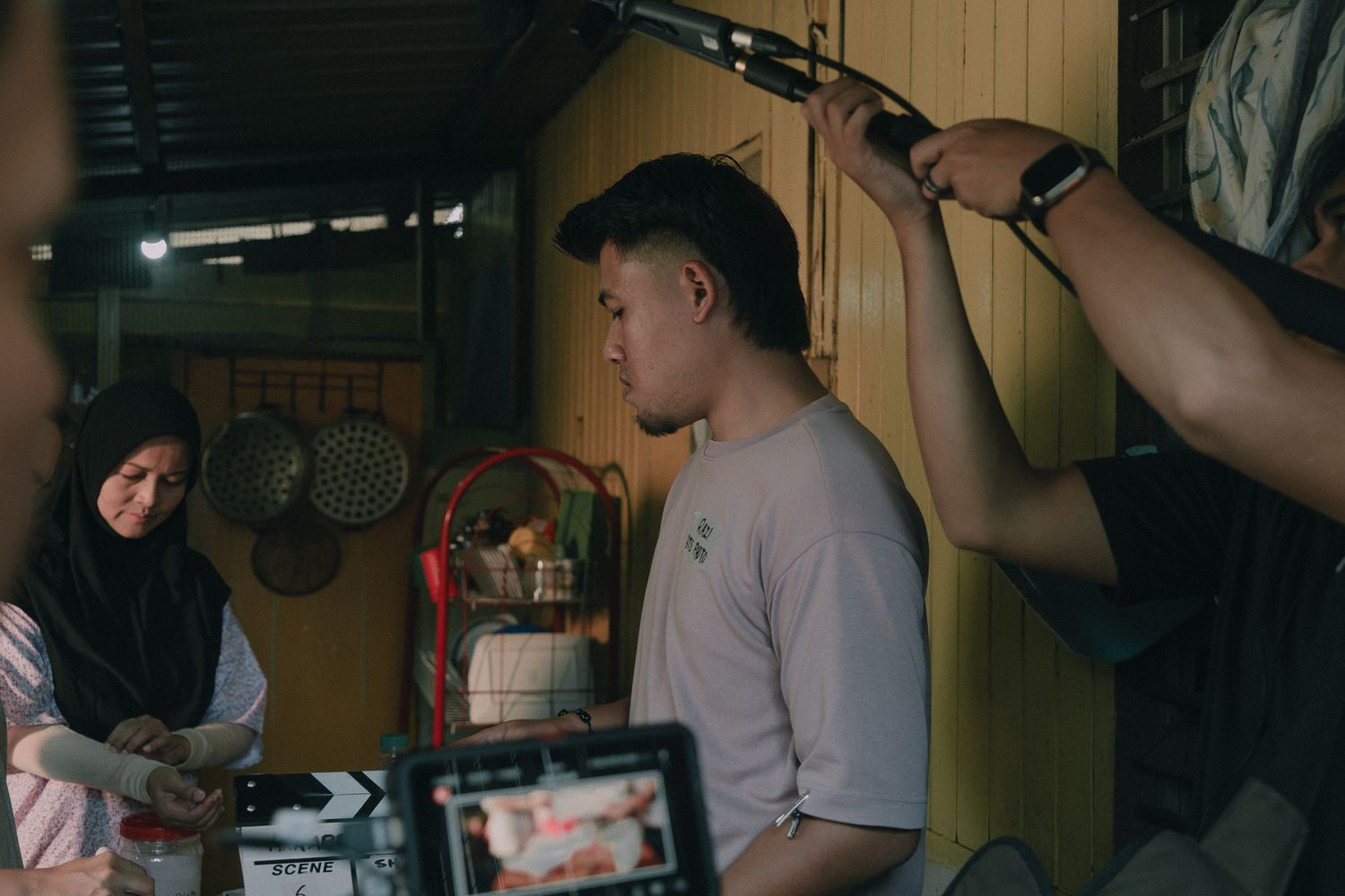 Film crew working in a dimly lit room with audio and video equipment during a production shoot.