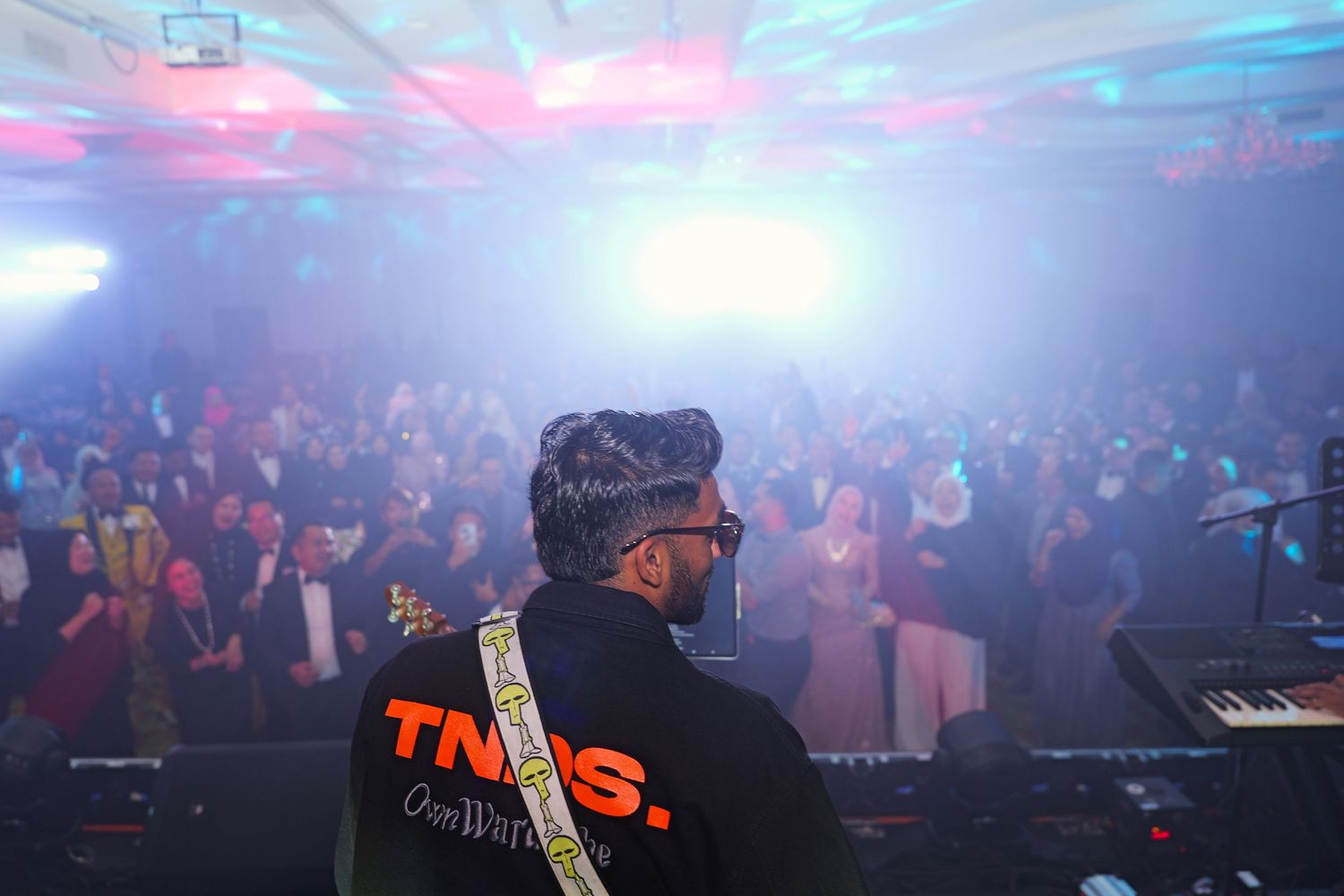 TNDS performer on stage facing a large crowd at an energetic corporate gala night.