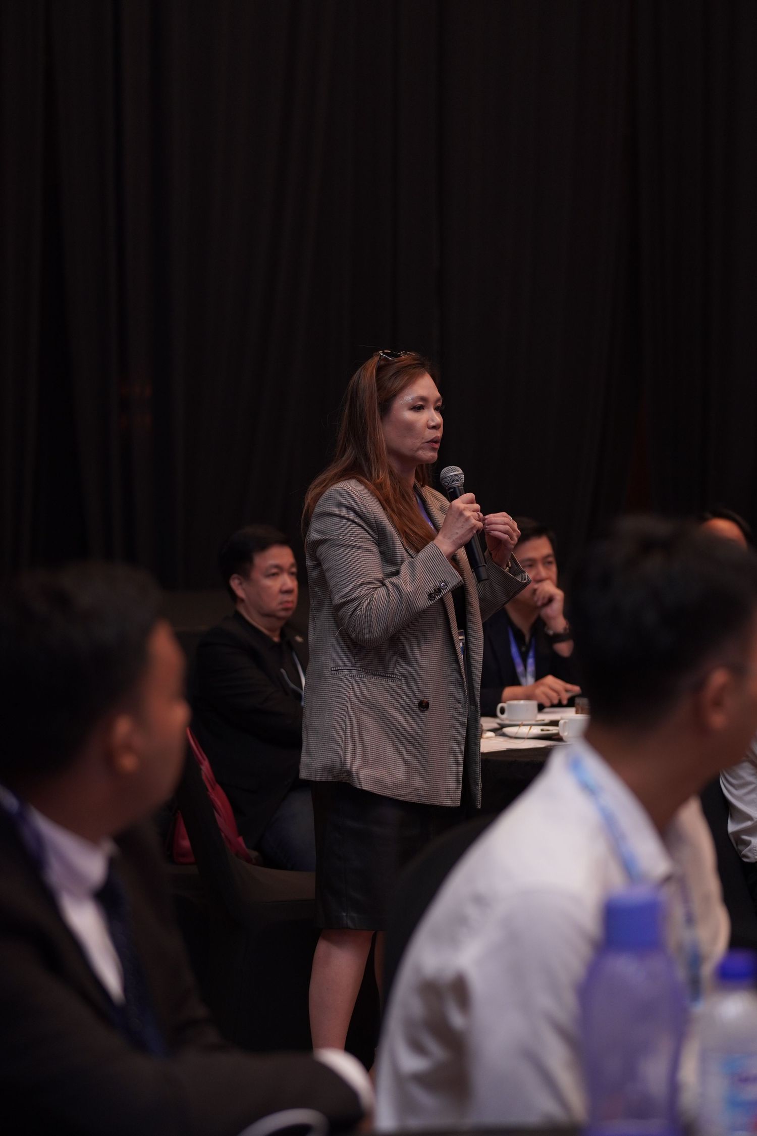 Conference attendees participating in a professional discussion session at a dimly lit venue.