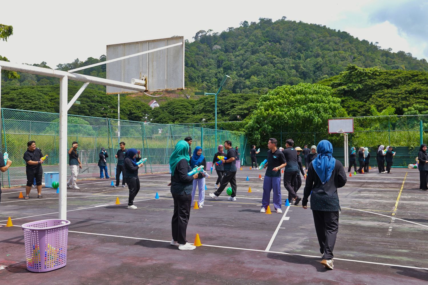 Team building outdoor activity with participants playing games on a sports court near hills.