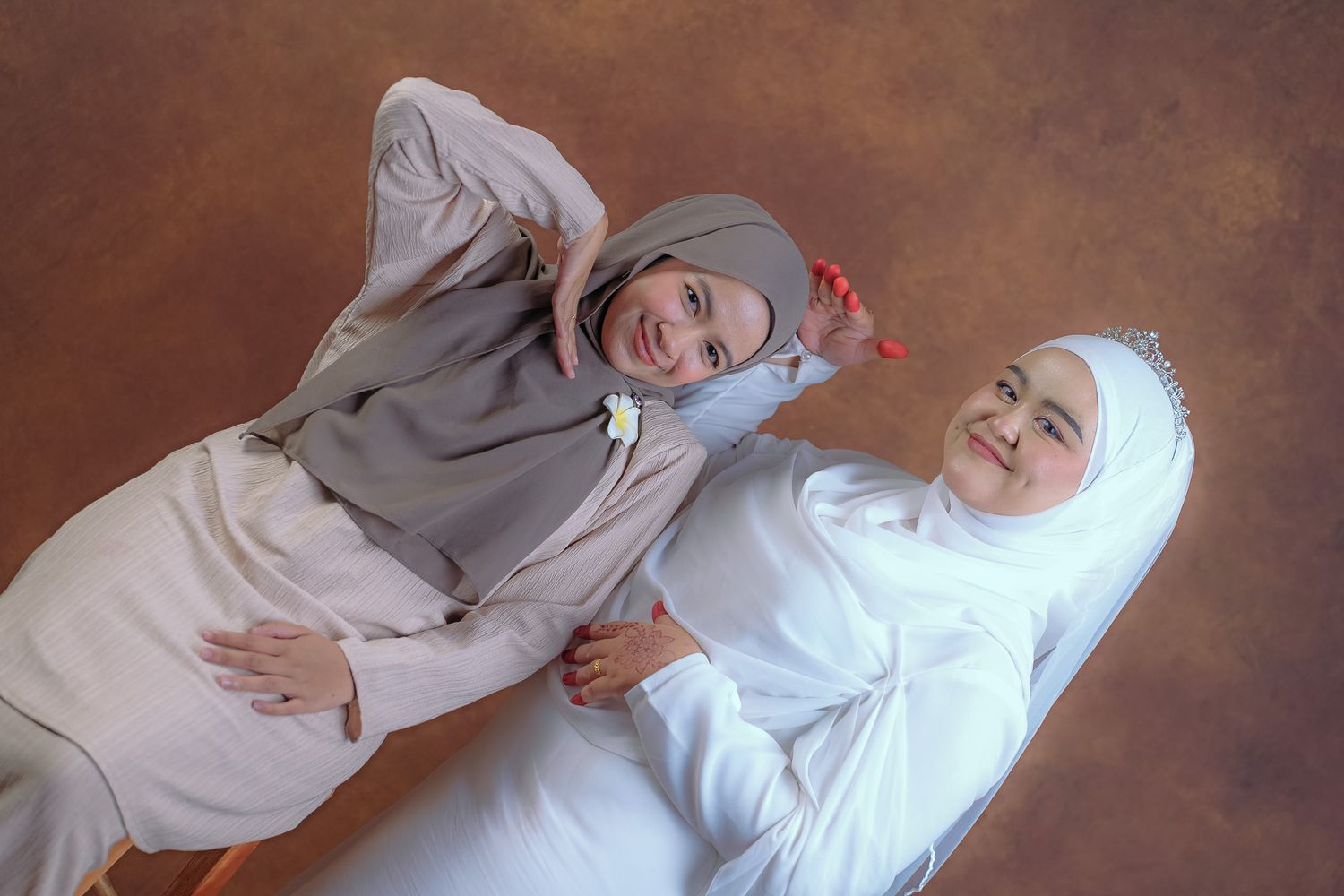 Candid moment of two women in hijabs laughing together during photo shoot.