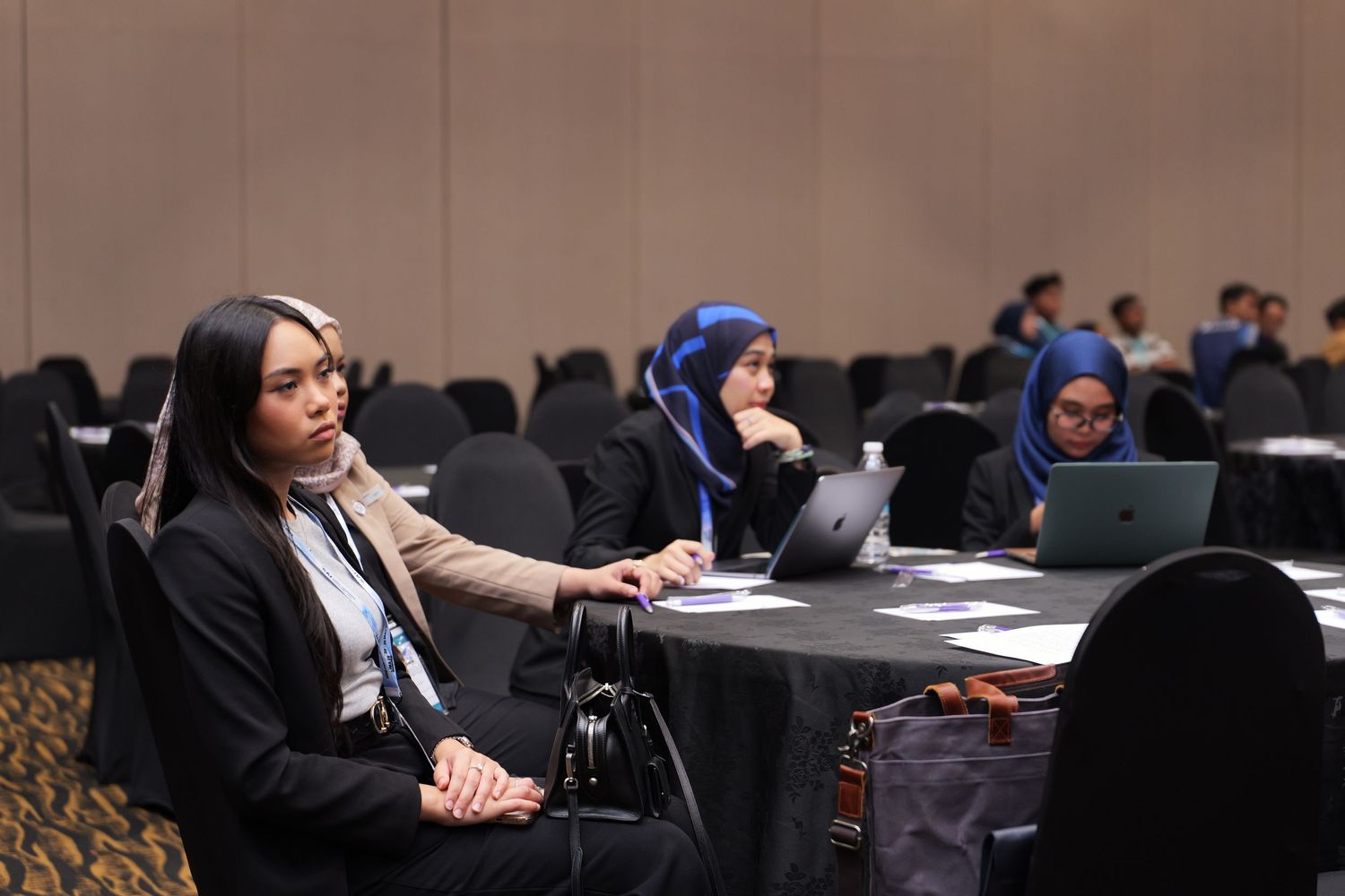 Professional conference participants work on laptops during a presentation session.