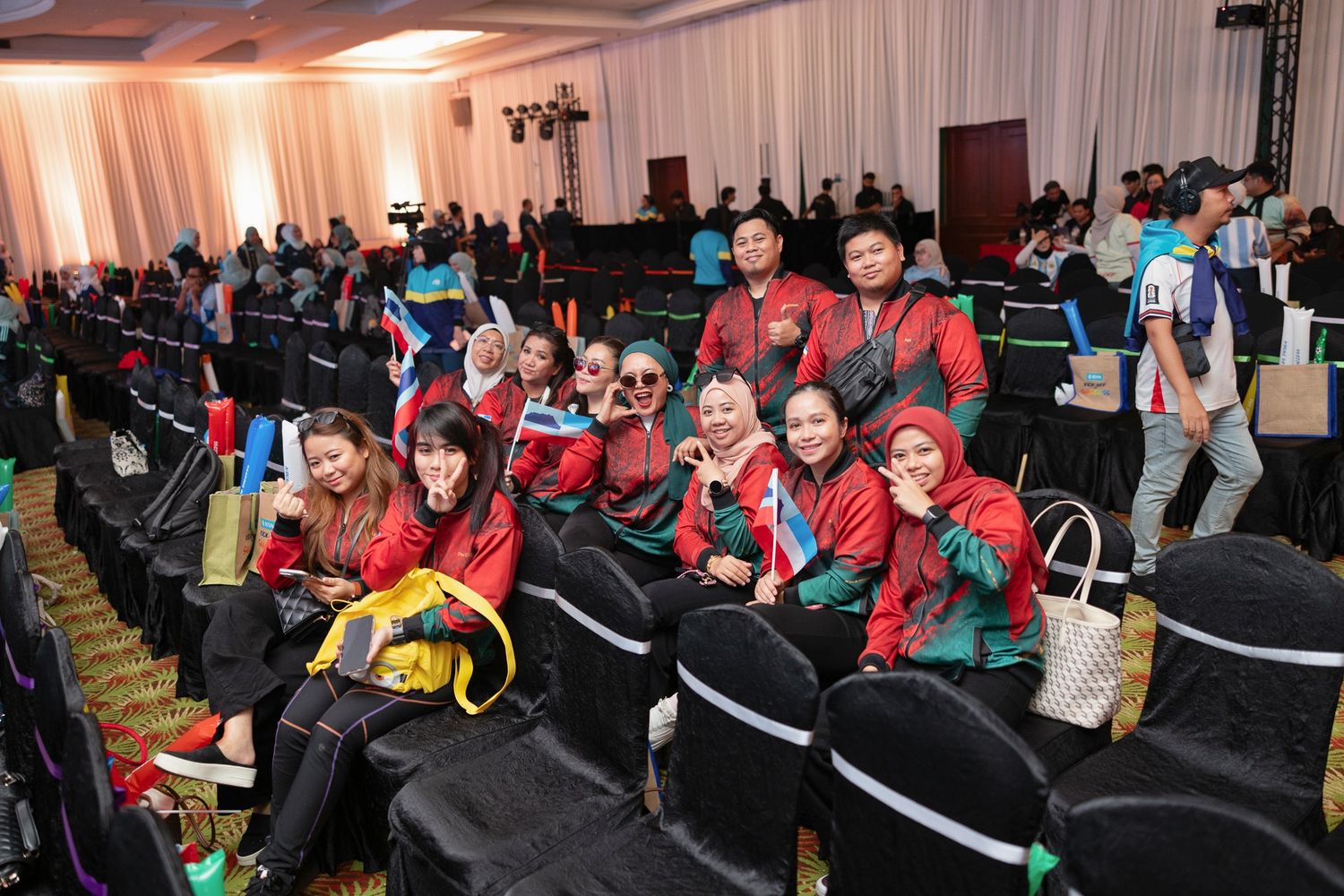Group of employees in red jackets pose together smiling at BSN corporate conference.