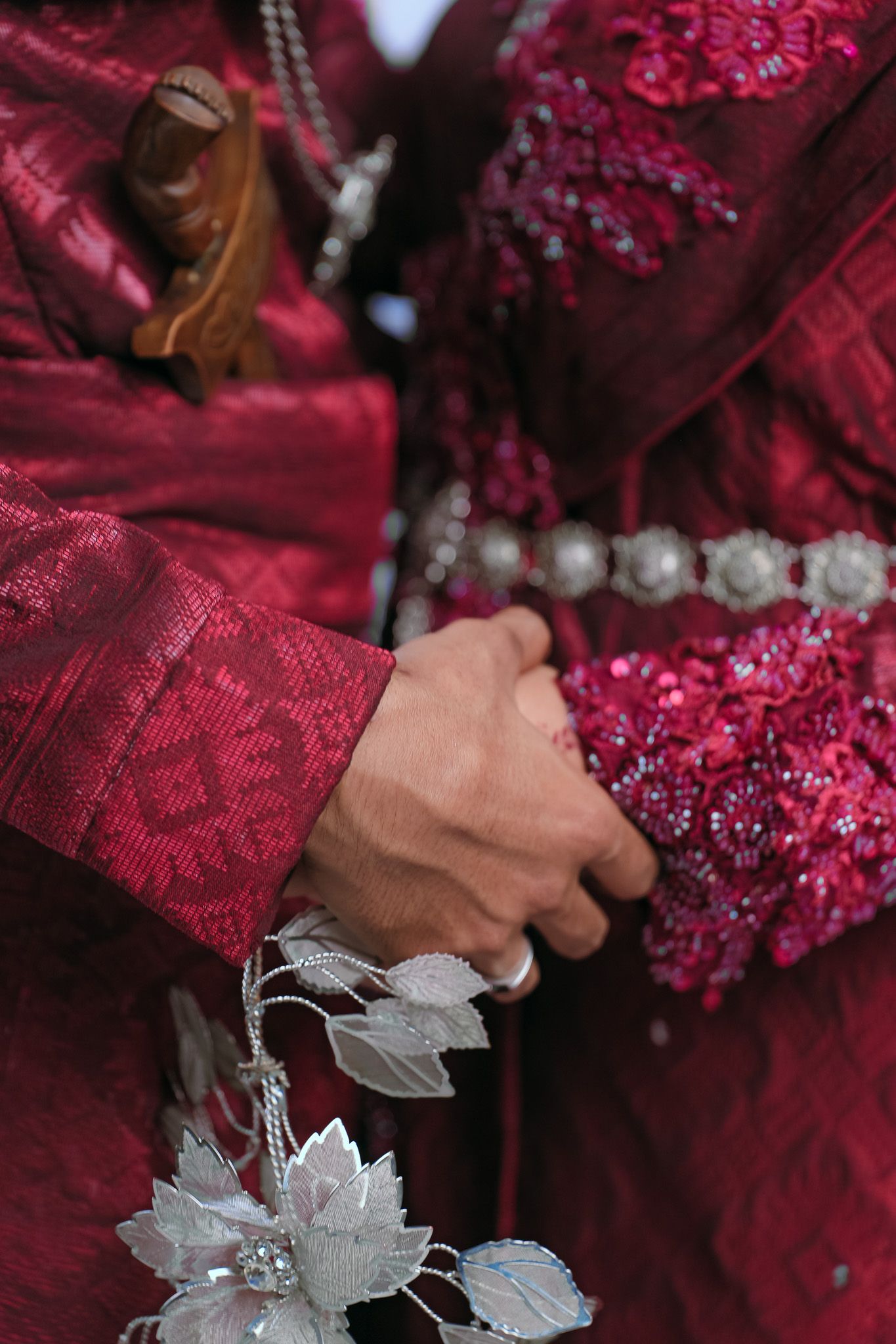 Close-up detail of a deep red embroidered dress with silver floral accents and pearl embellishments.
