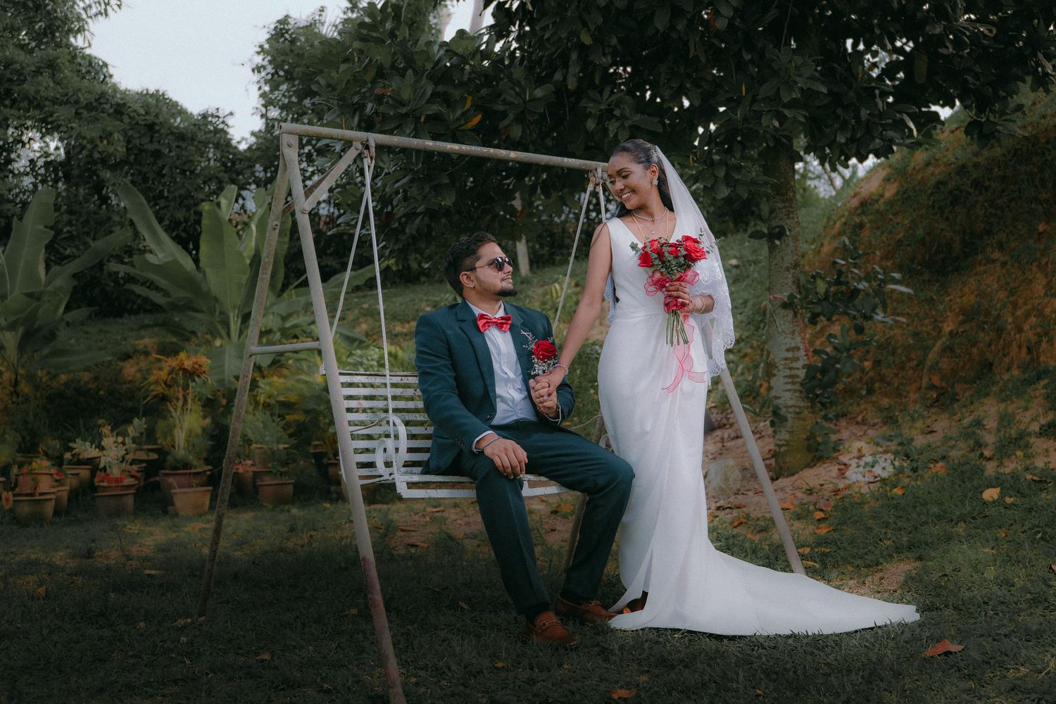 Wedding couple poses creatively on a wooden swing in an outdoor garden setting.