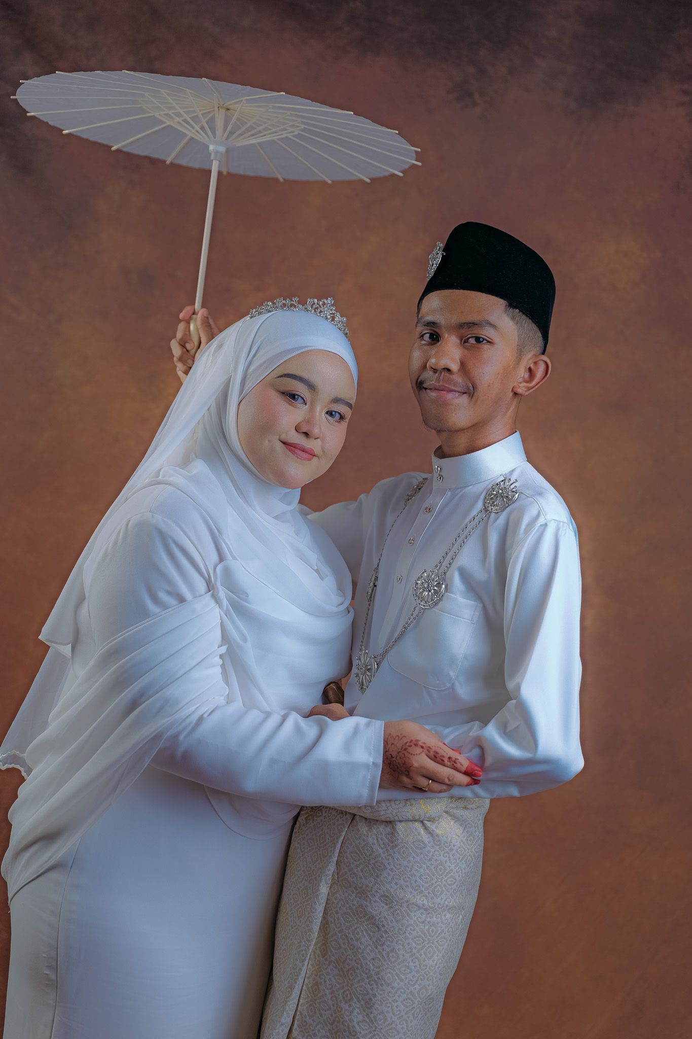 A romantic wedding photoshoot featuring a couple in traditional white Muslim attire and a decorative parasol.