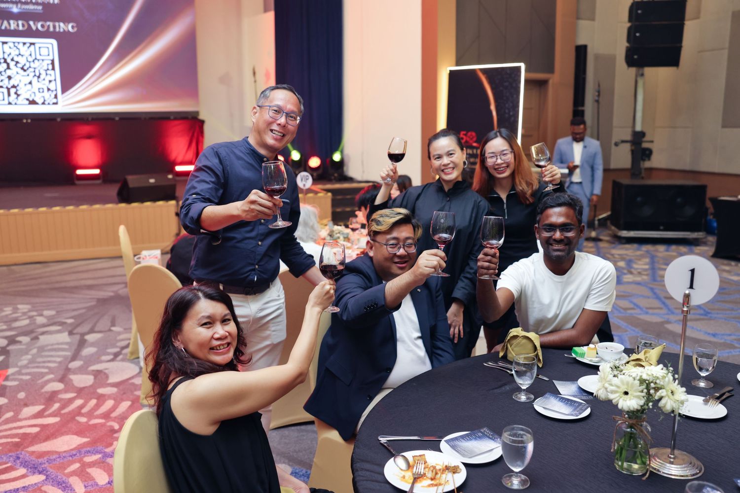 Diverse group of colleagues toasting with wine glasses at corporate gala dinner celebration.