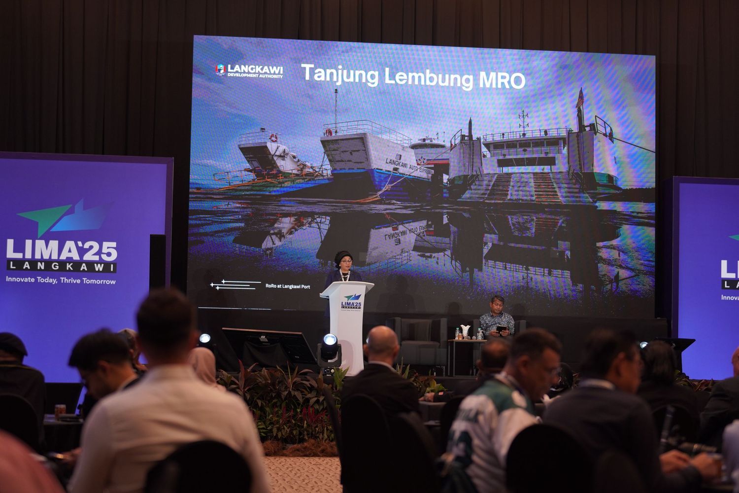 Presentation slide showing military aircraft during LIMA25 conference with audience in foreground.