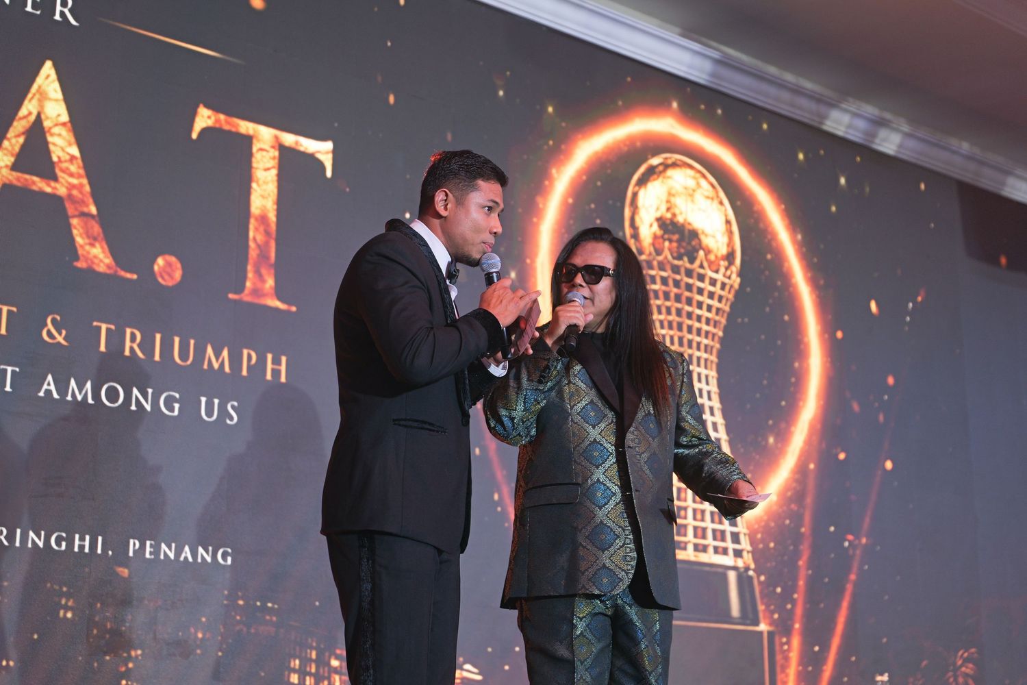 Two speakers present on stage at G.A.T. Triumph corporate awards event in Penang.