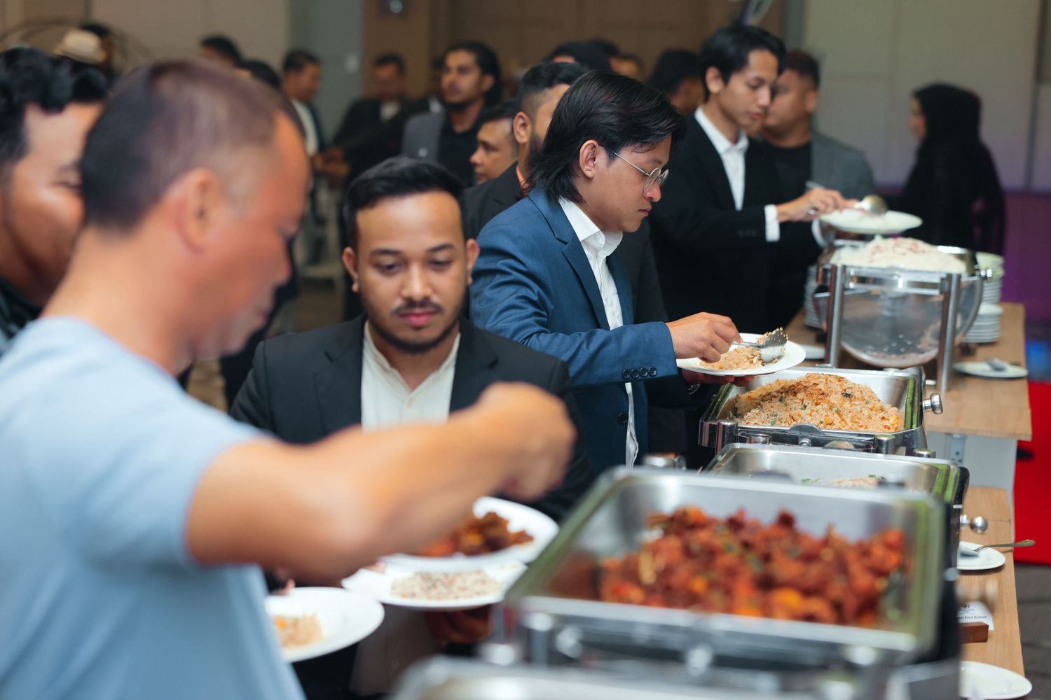 Business professionals serving themselves at a buffet line during a corporate catering event.