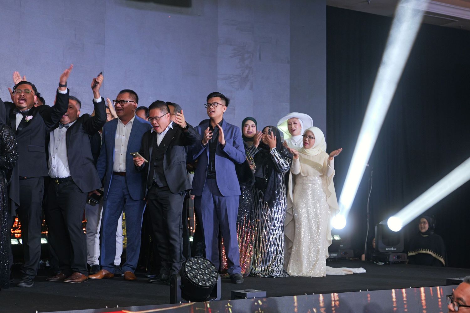 Excited group of corporate leaders celebrate on stage at an awards gala event.