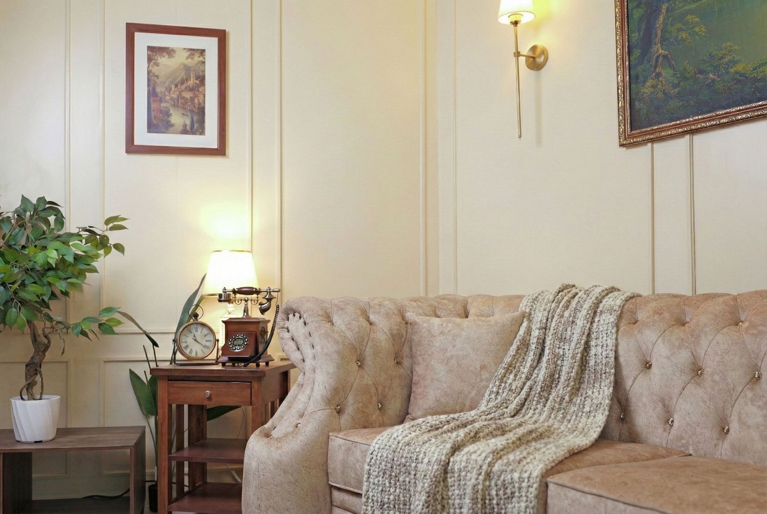 A cozy living room interior with beige tufted furniture, wall art, and soft lighting creating a warm ambiance.