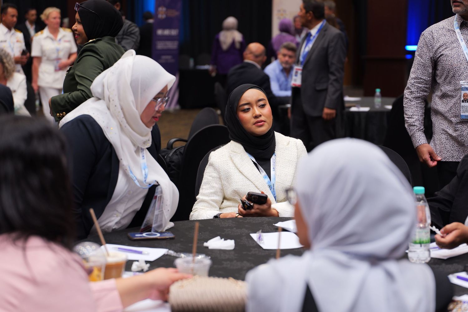Diverse group of attendees engaged in discussion at round tables during a professional conference.