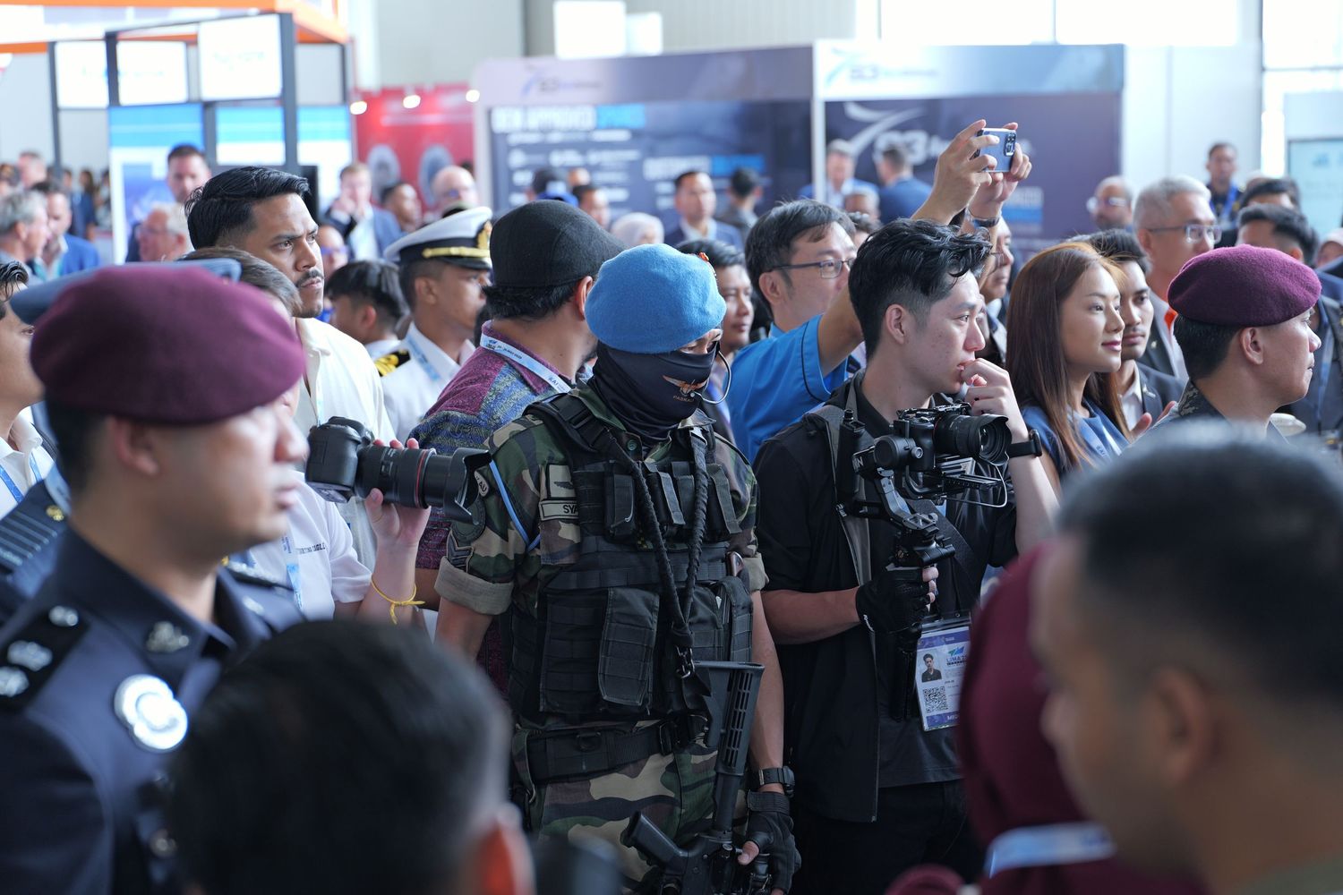 Military and law enforcement personnel in various uniforms gather at a crowded indoor event.