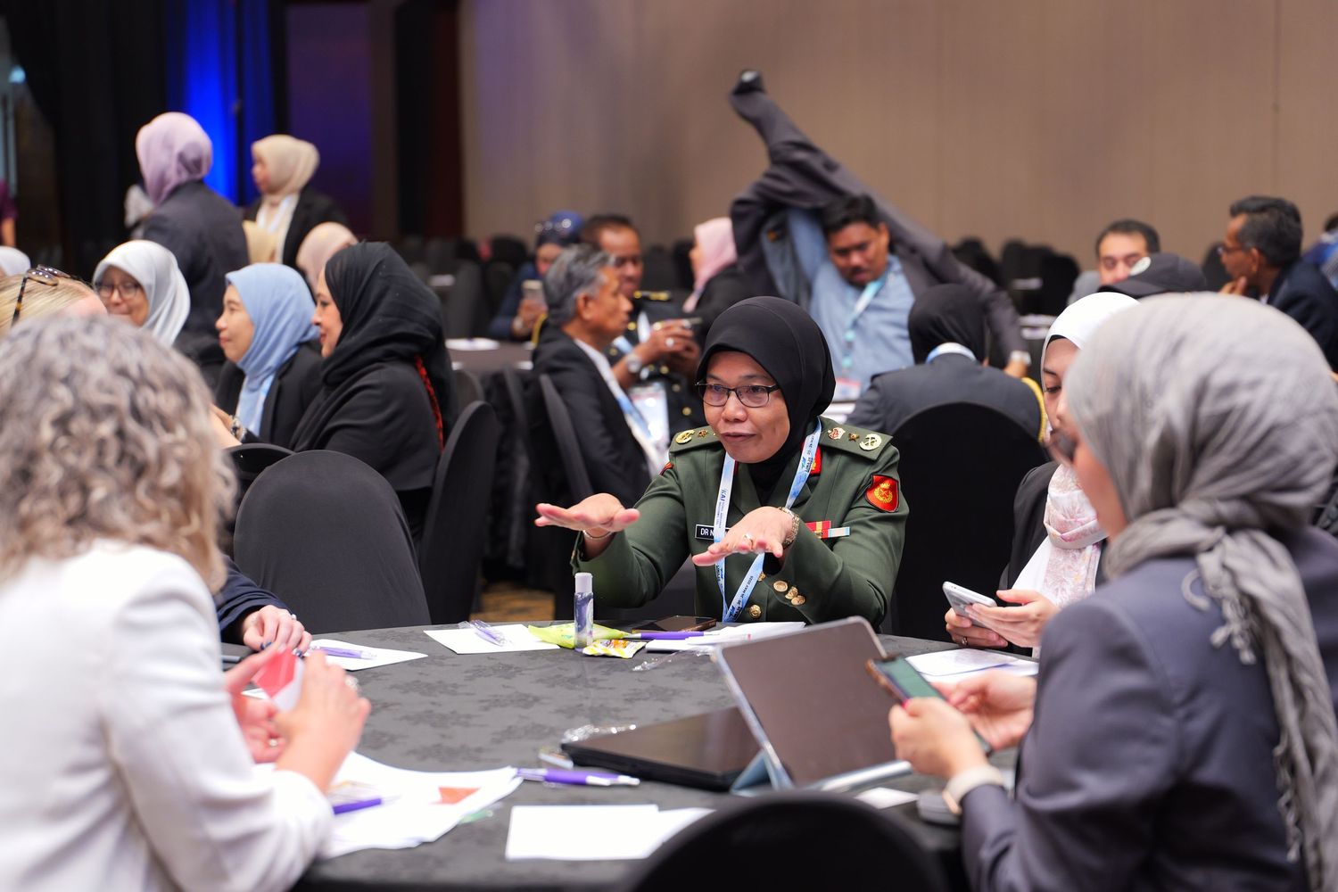 Conference attendees seated at round tables participate in an interactive discussion session.