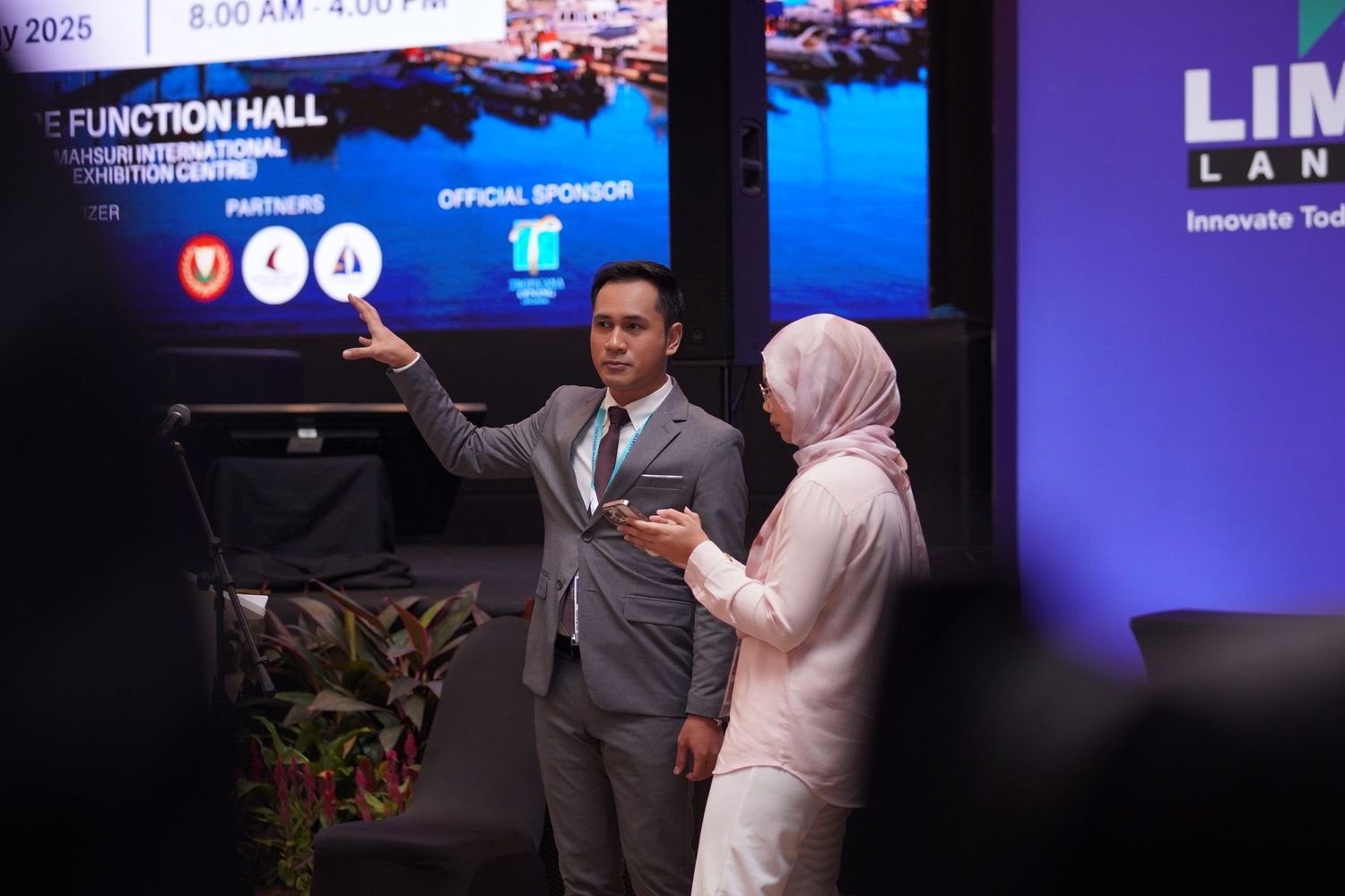 Speakers giving presentation in front of digital display at technology conference.