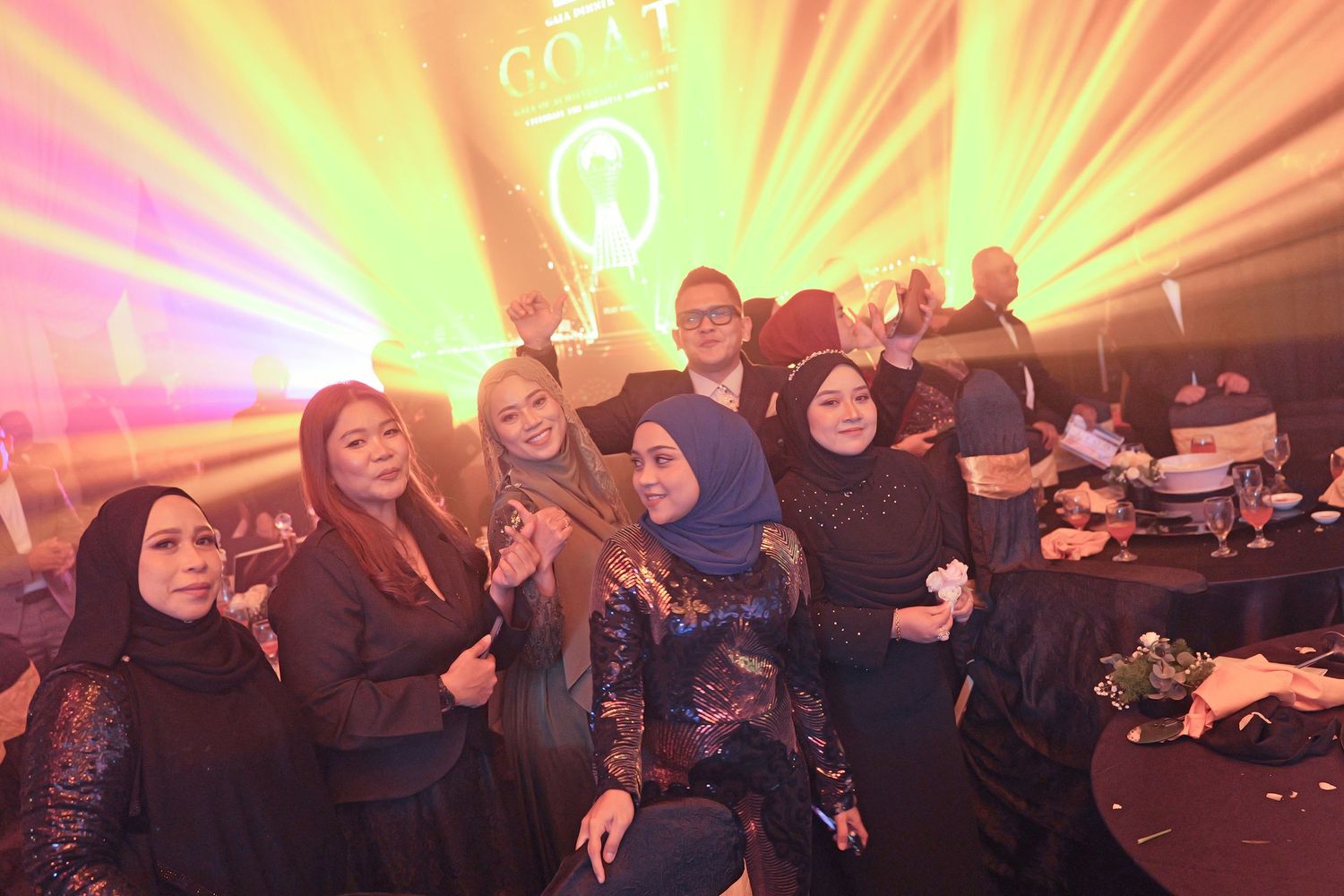 Group of colleagues posing together under dramatic laser lights at a corporate awards gala.