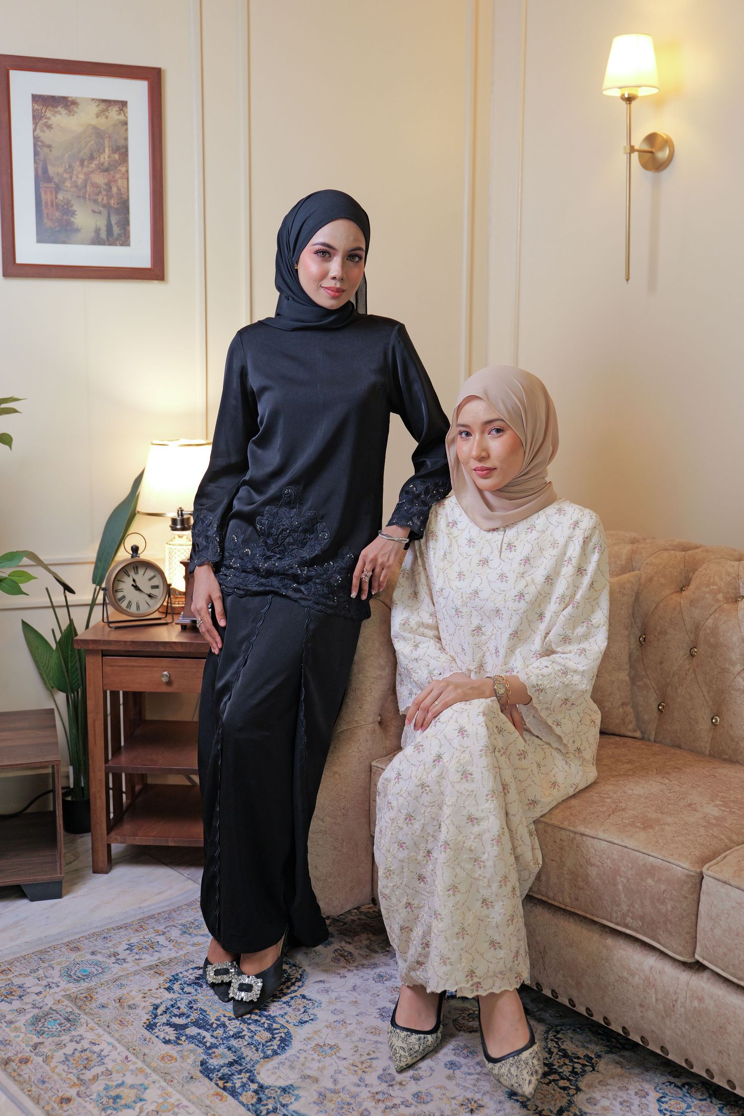 Two people in traditional modest dress sit together on a beige couch in a cozy living room setting.