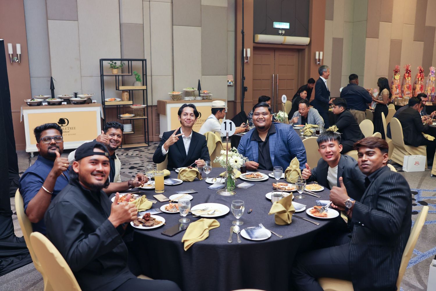 Group of colleagues smiling and posing at a round dinner table during corporate banquet.