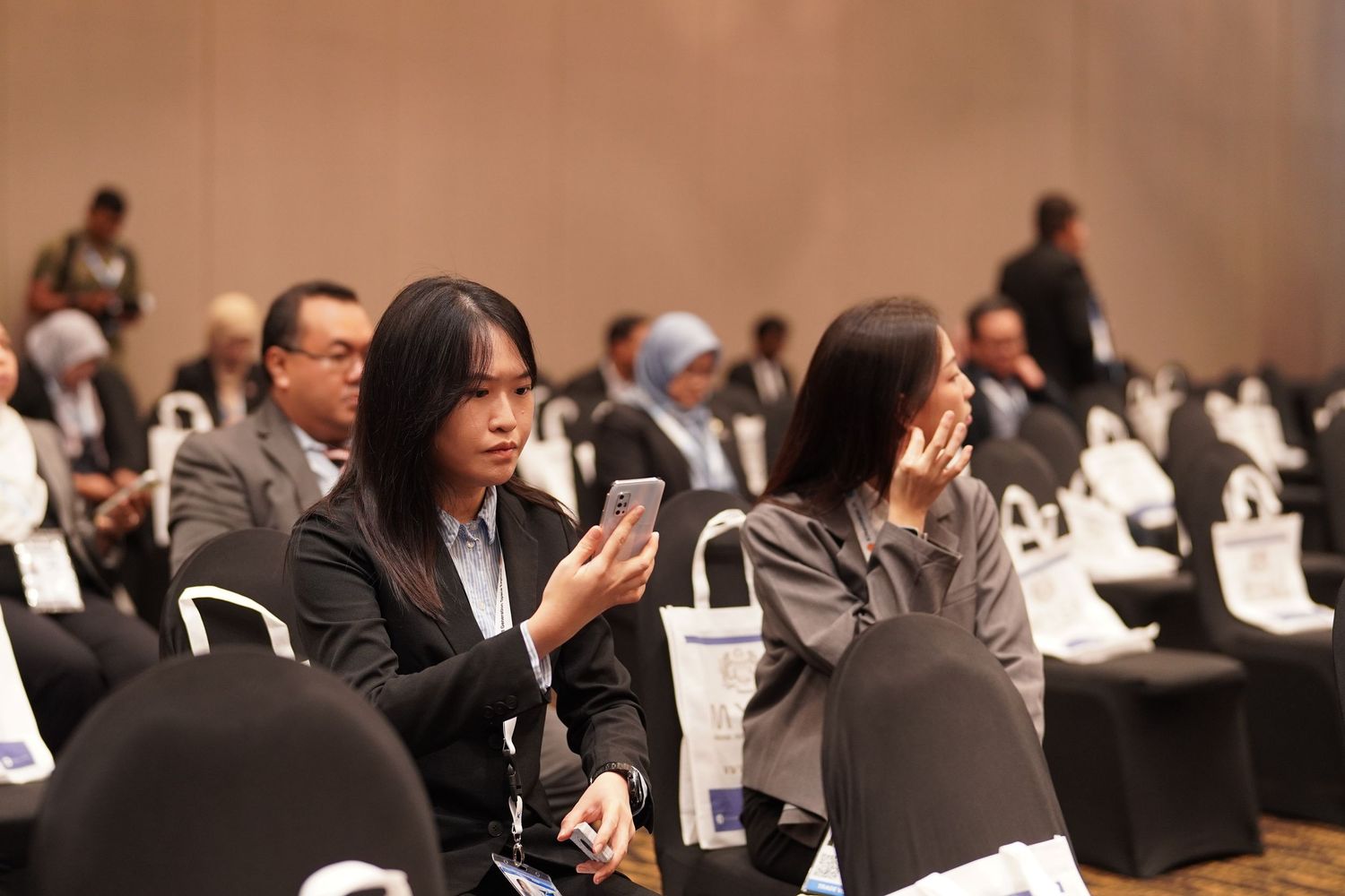 Conference attendees using mobile phones and devices during a professional business event.