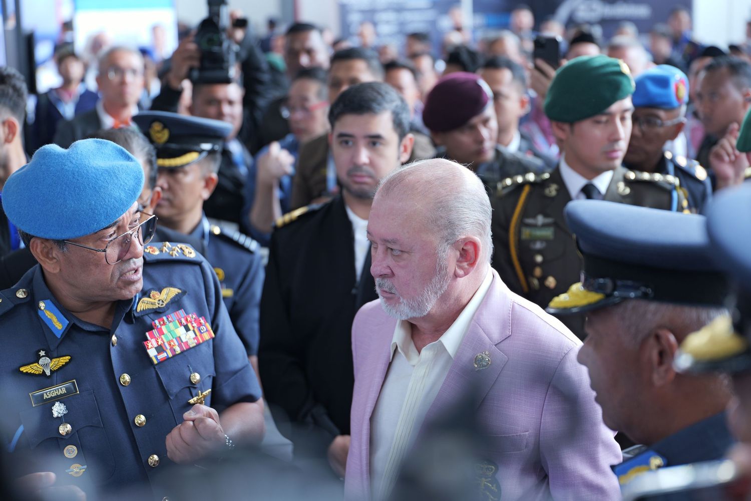 Military personnel and officials gather at a formal event wearing various uniforms and dress attire.