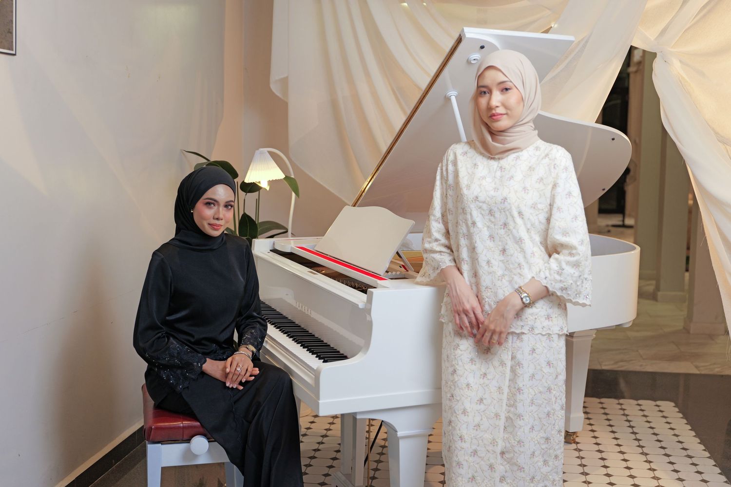 Two people in traditional modest dress pose near a white grand piano in an elegant room.