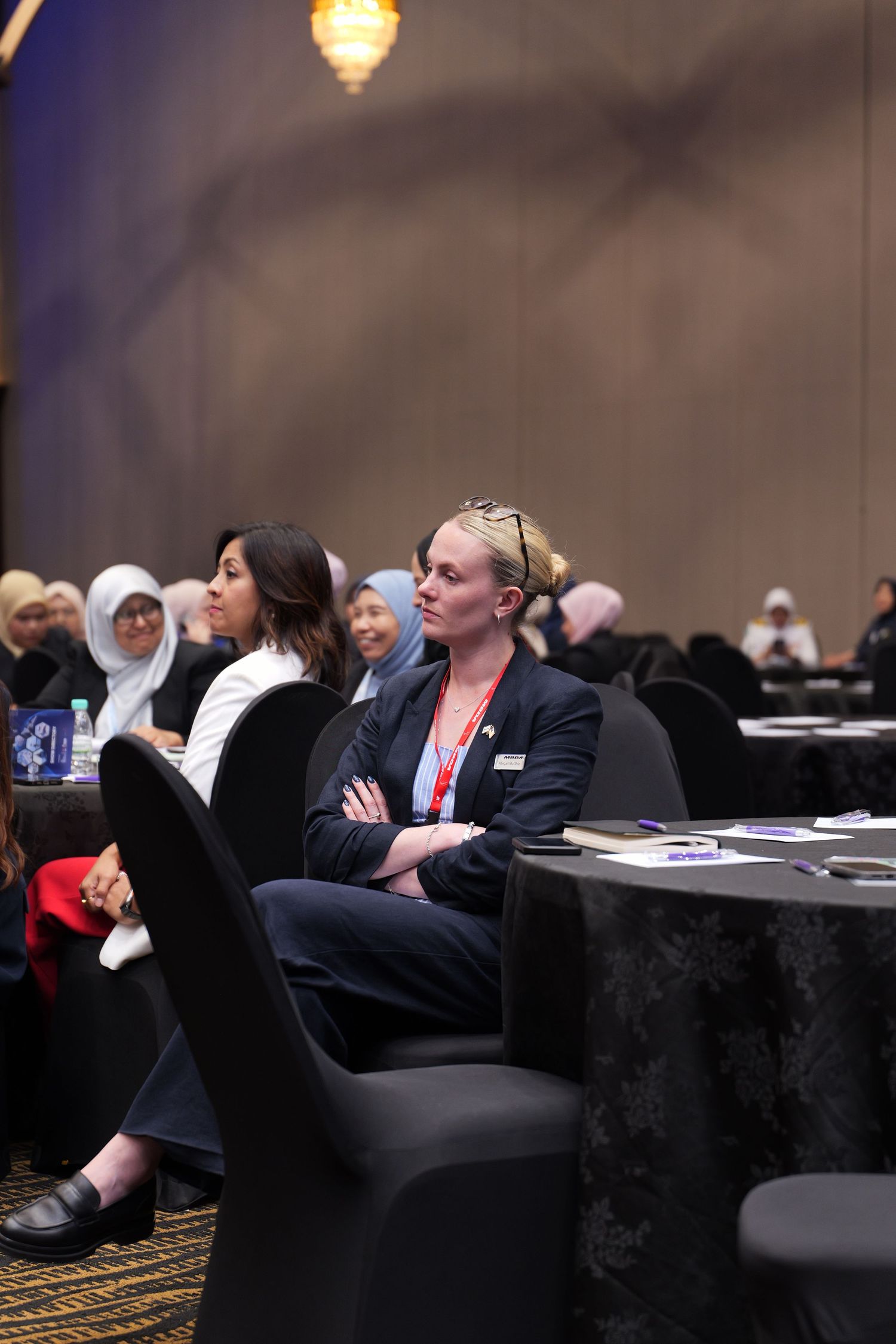 Diverse group of professionals seated at round tables during a conference or seminar.