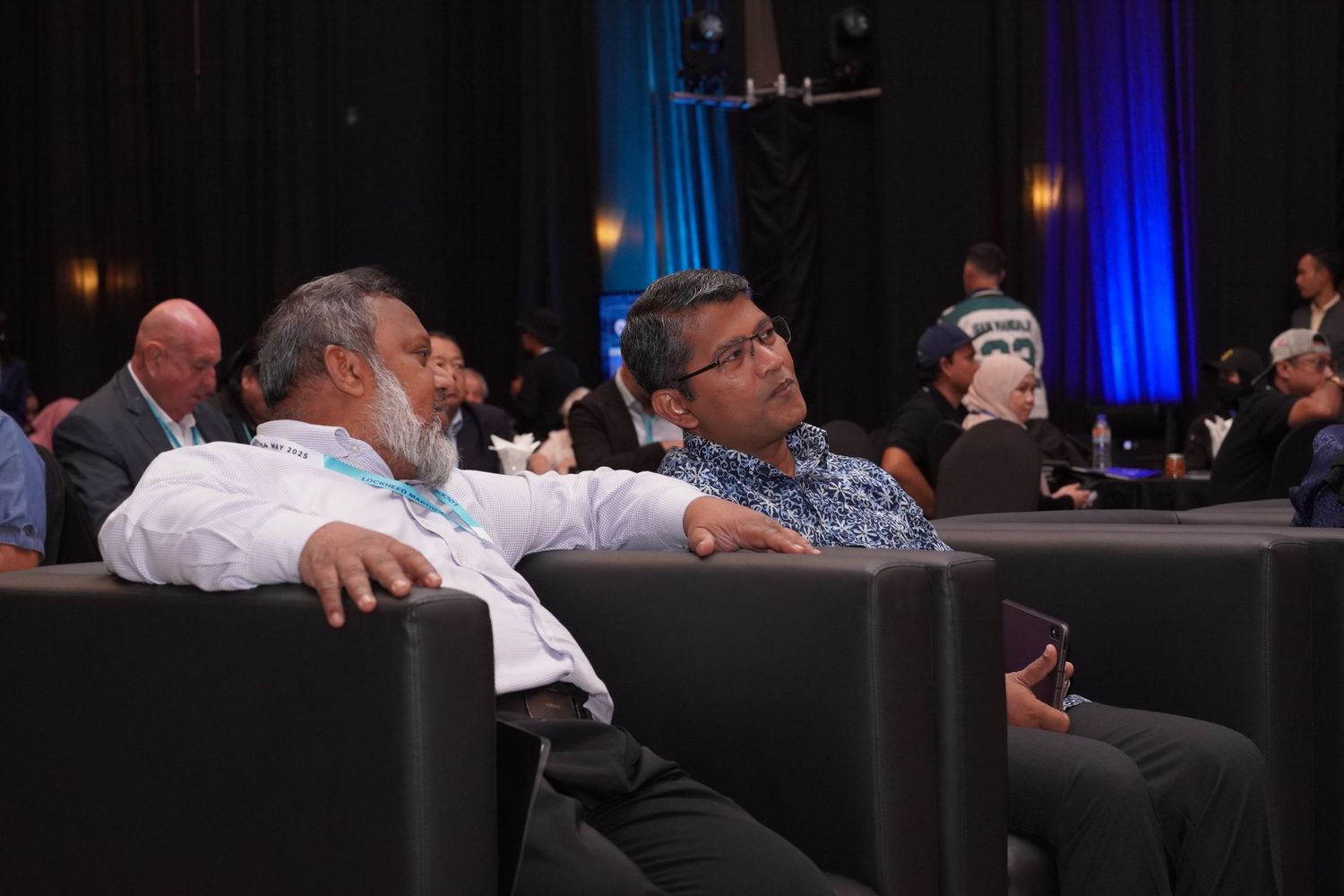 Attendees relaxing in conference chairs during event break.
