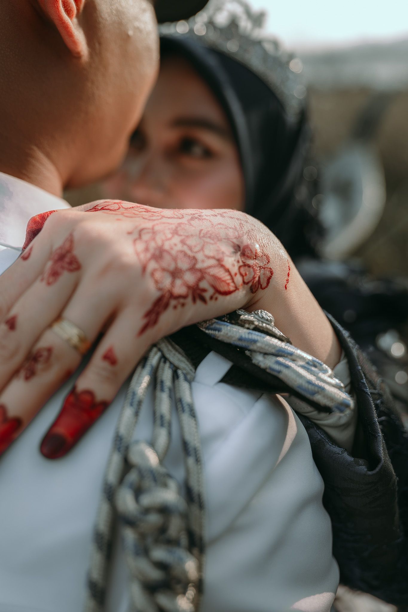Close-up of a hand adorned with intricate henna designs resting on fabric.