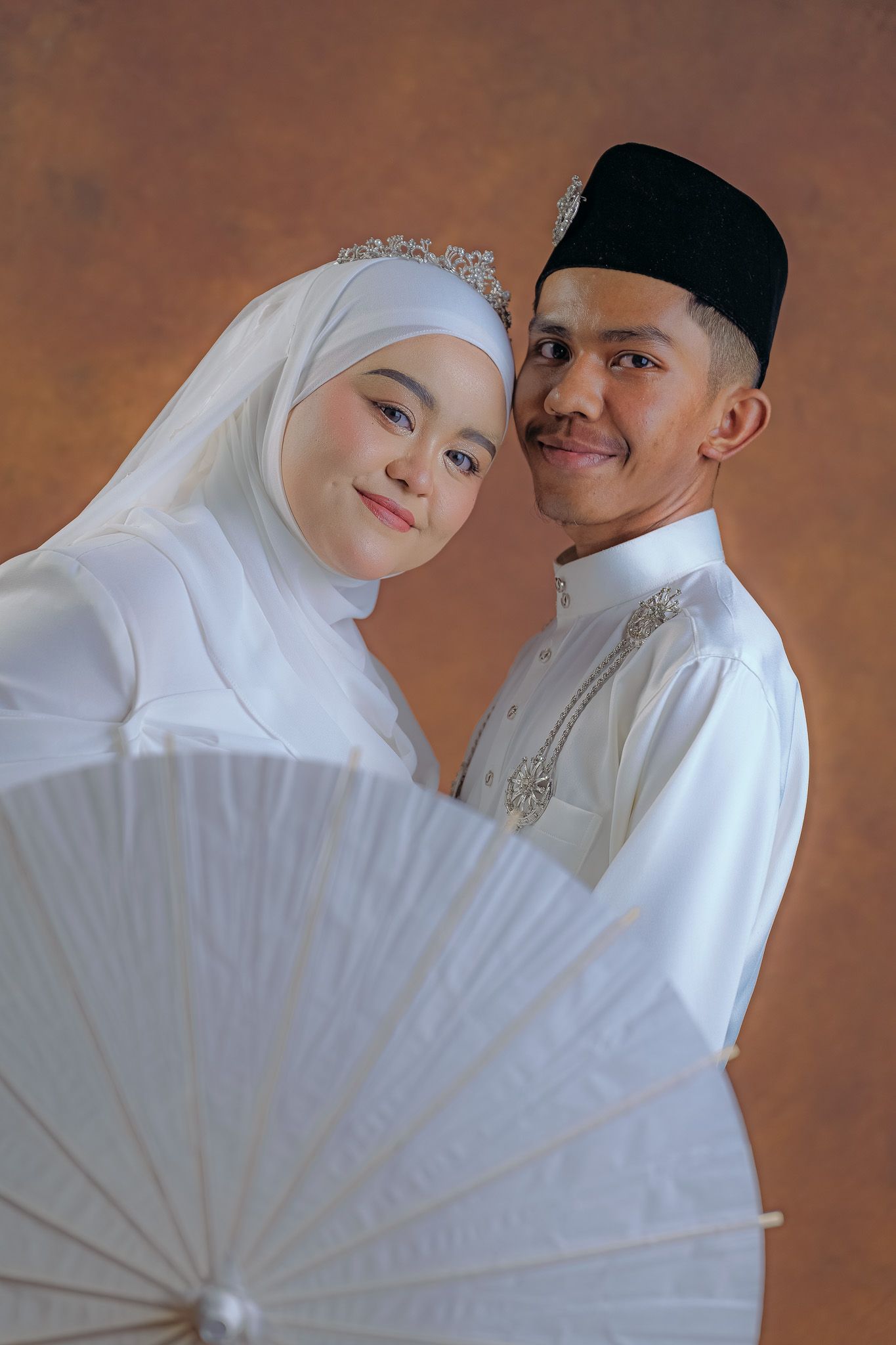 Muslim wedding photo series featuring white parasol and traditional attire against warm brown background.