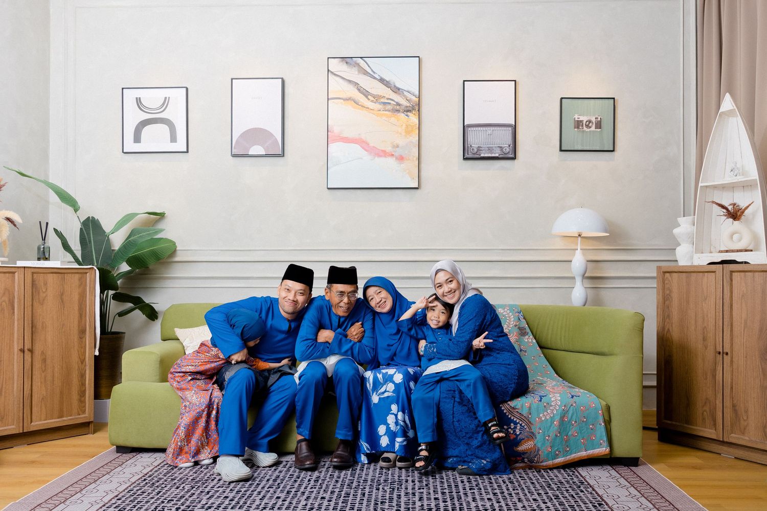 A group of people wearing blue uniforms sit together on a gray couch in a modern office setting.