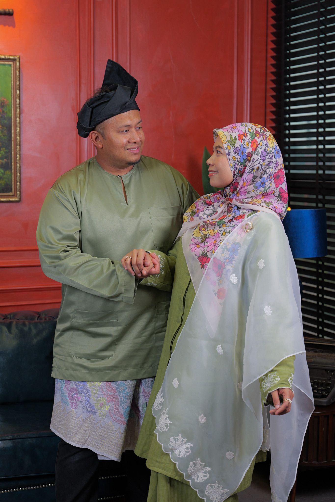 Four sequential images showing two people in matching green outfits having a conversation against a red wall.
