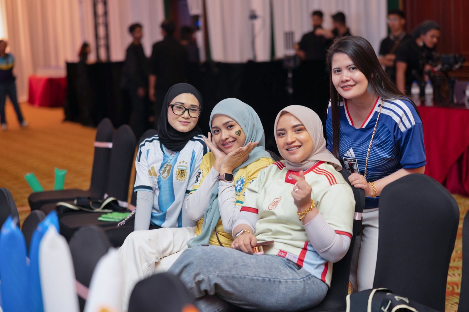 Four smiling women in sports jerseys pose together at a corporate team building event.