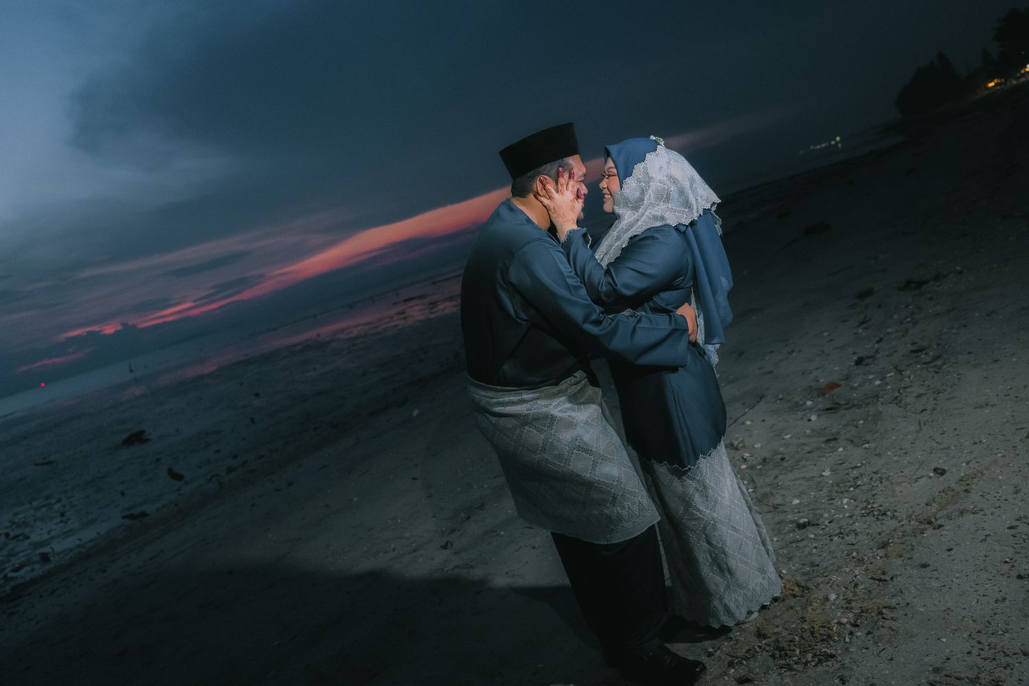Two people embrace on a dark volcanic landscape with glowing red lava flows visible in the background.