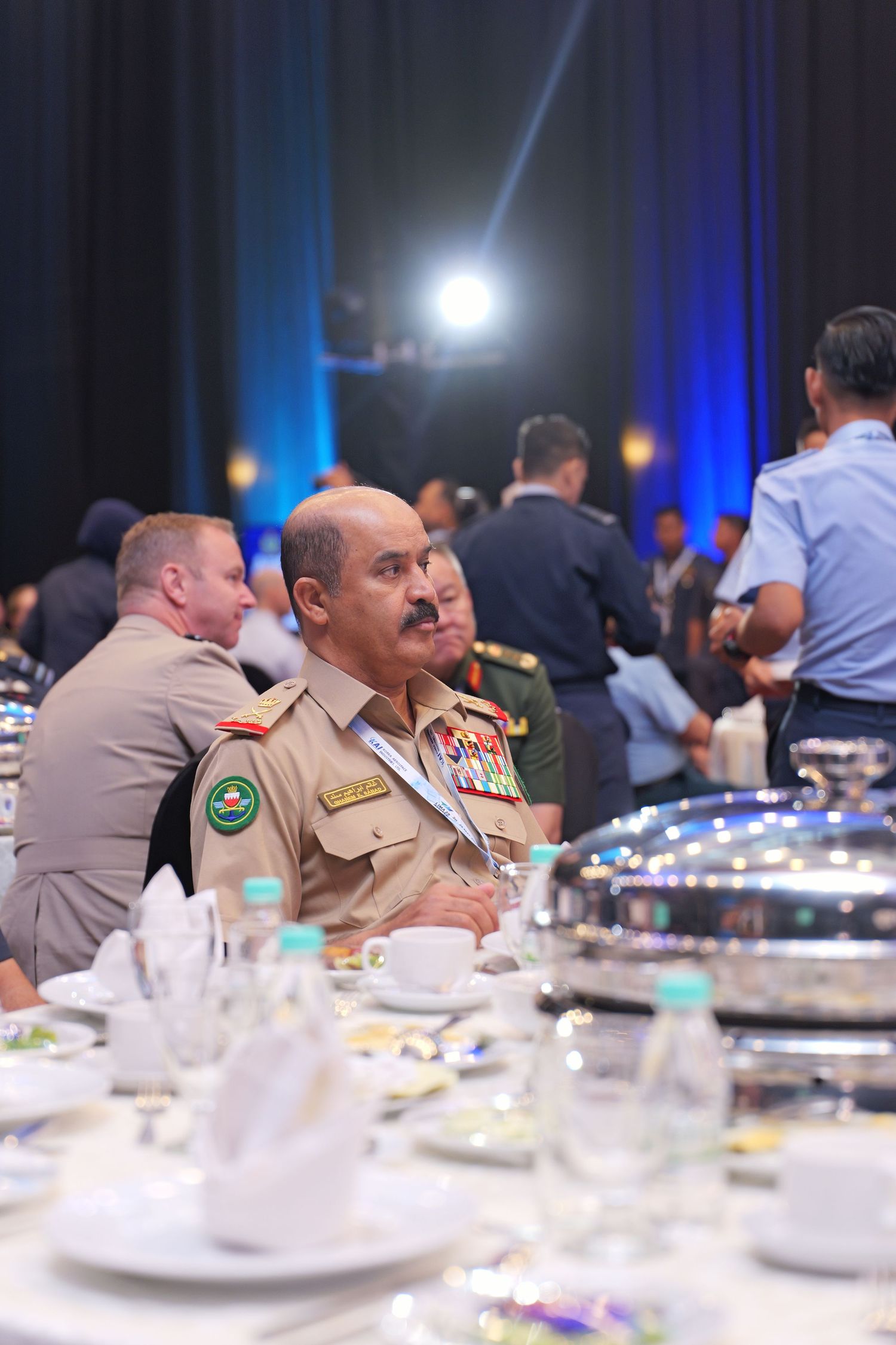 Military officer in formal uniform seated at elegant dining table during conference event.