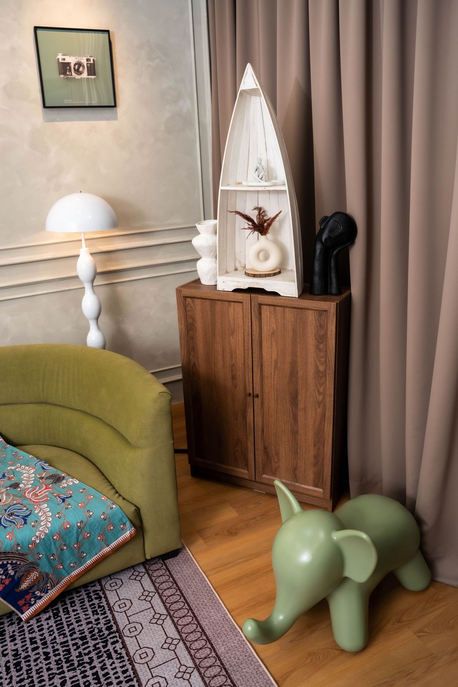 Modern living room corner with olive green chair, wooden cabinet, and decorative dinosaur figures in soft lighting.