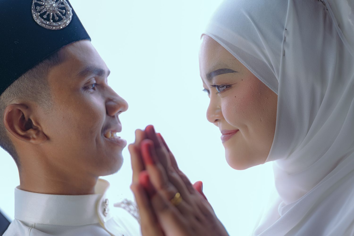A Muslim couple in traditional white attire shares a tender moment during their wedding ceremony.