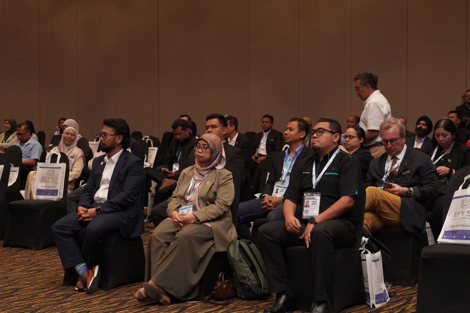 Conference attendees seated in rows during a professional business event in an auditorium.