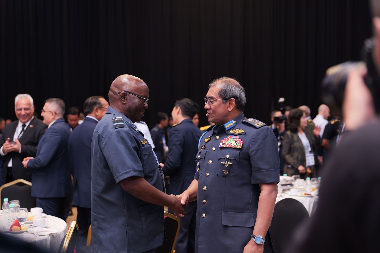 Military personnel in formal uniforms exchanging handshakes during a professional networking event.