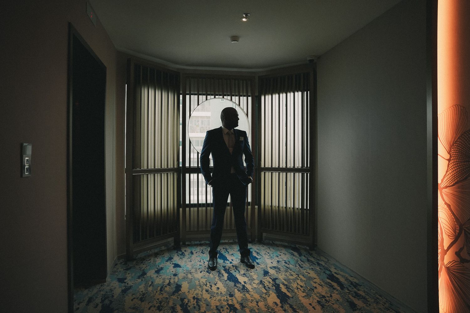 Dark eerie corridor with vertical bars and ominous lighting showing a silhouetted figure at the end.