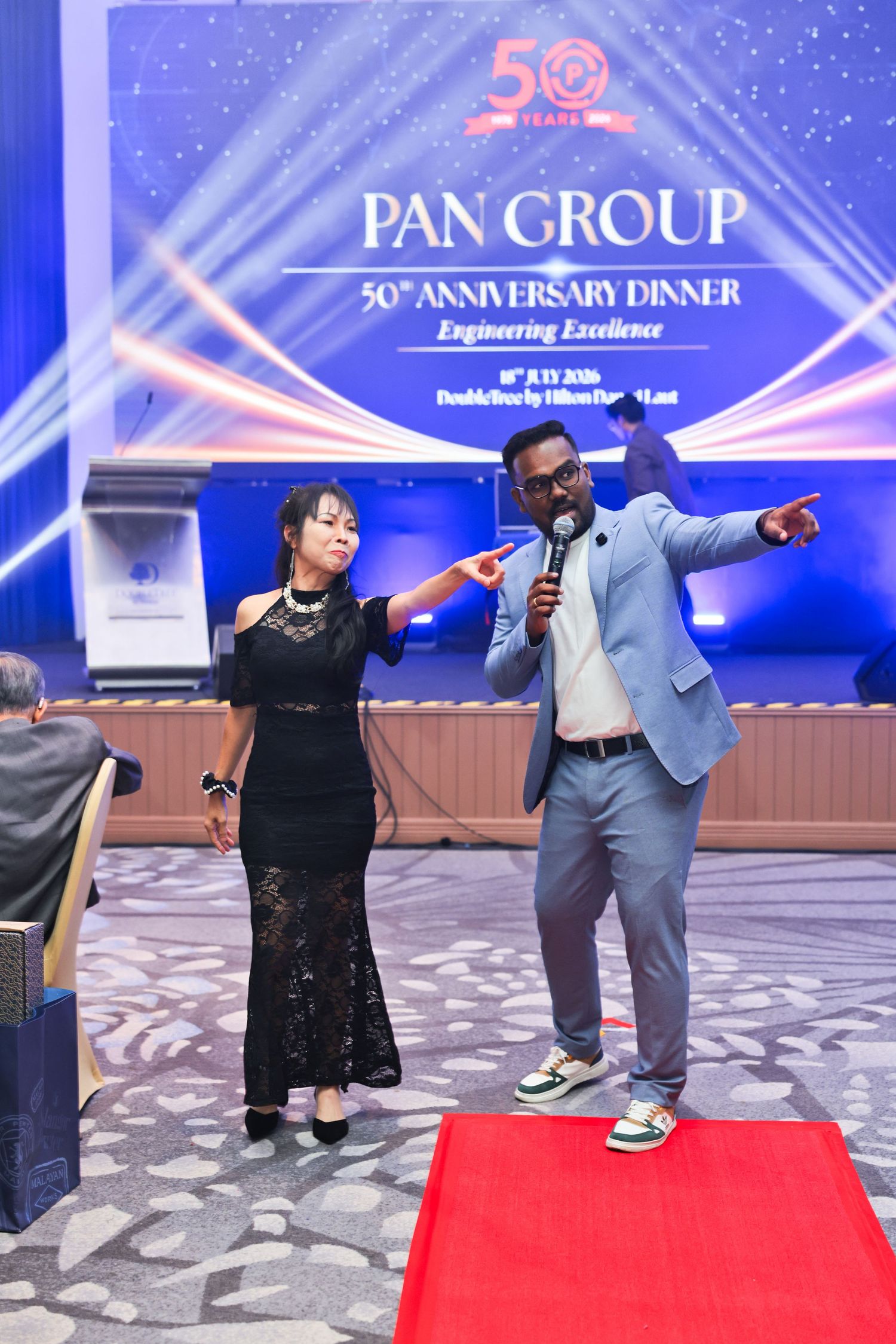 A host and guest perform on stage at Pan Group 50th Anniversary Dinner gala event.
