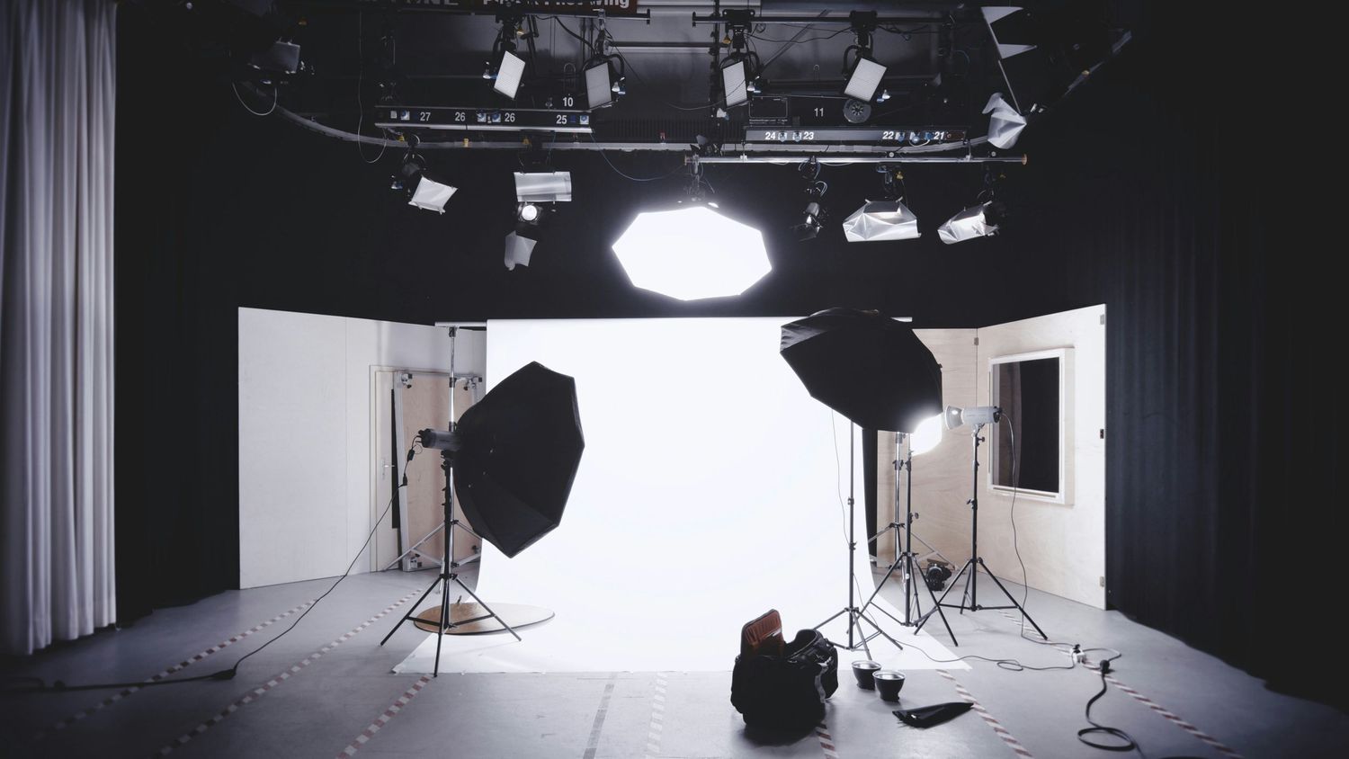 A panoramic view of a professional photography studio setup with lighting equipment and white backdrops.