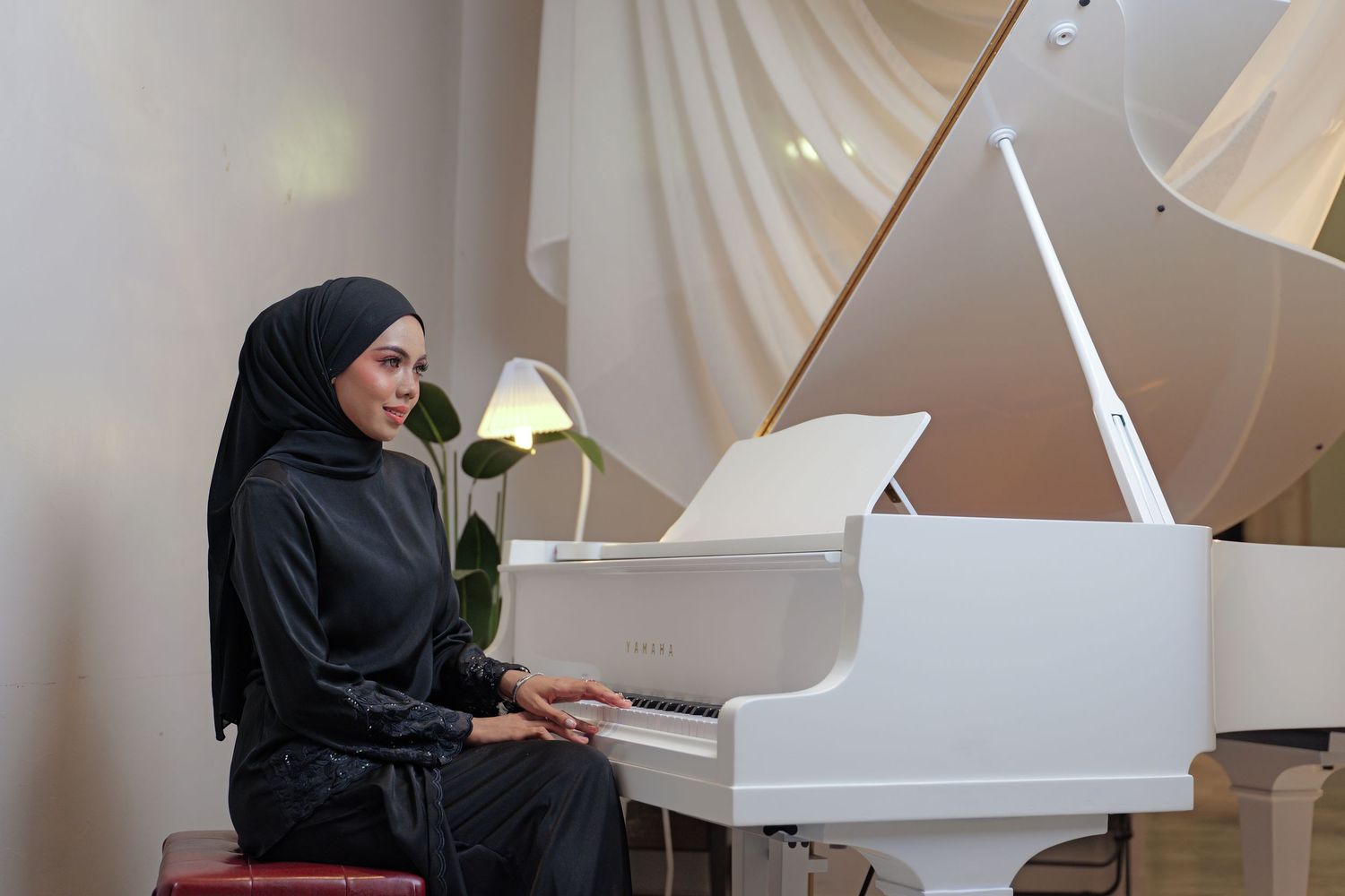 A white grand piano sits in an elegantly decorated room with soft natural lighting.