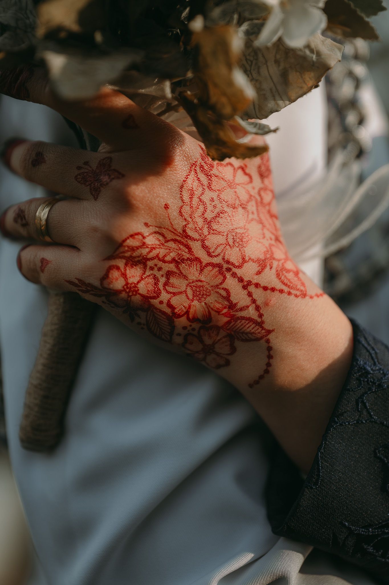 Close-up view of red henna designs on neck showcasing intricate floral and geometric patterns on skin.