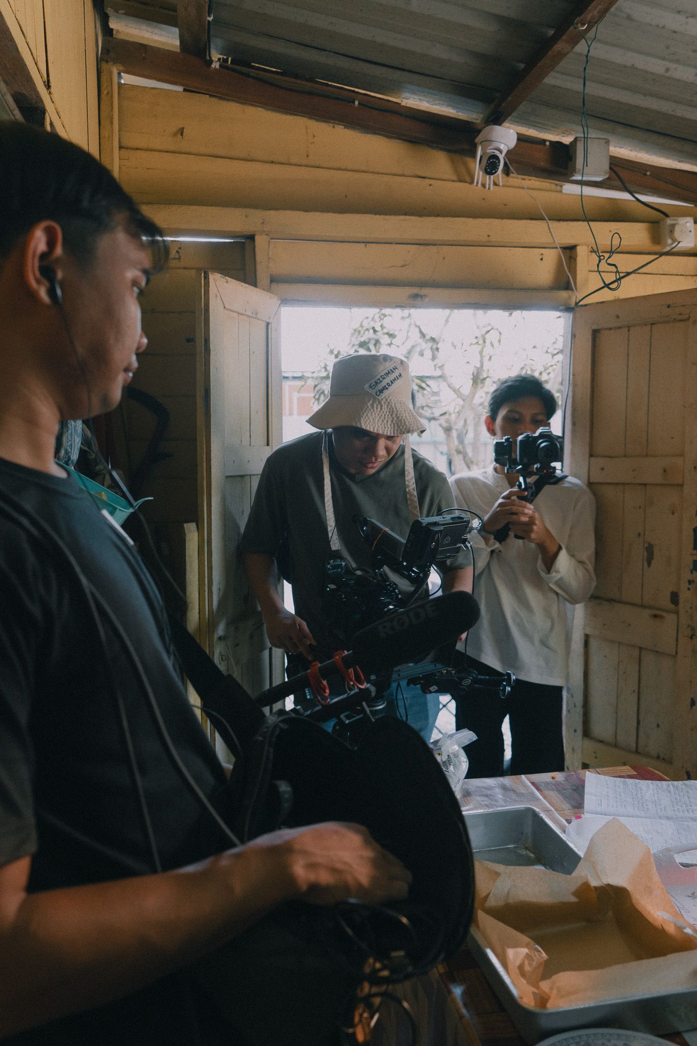 Behind the scenes video production team working with cameras and equipment in a wooden interior space.