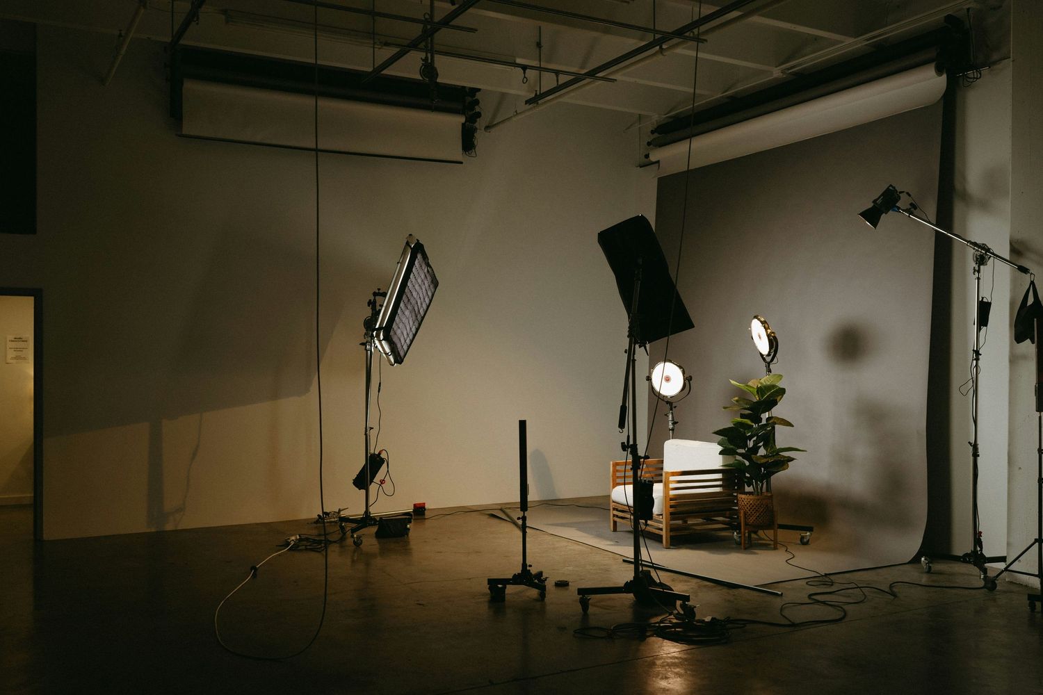Professional photo studio setup with lighting equipment, backdrops, and camera gear in a spacious industrial space.
