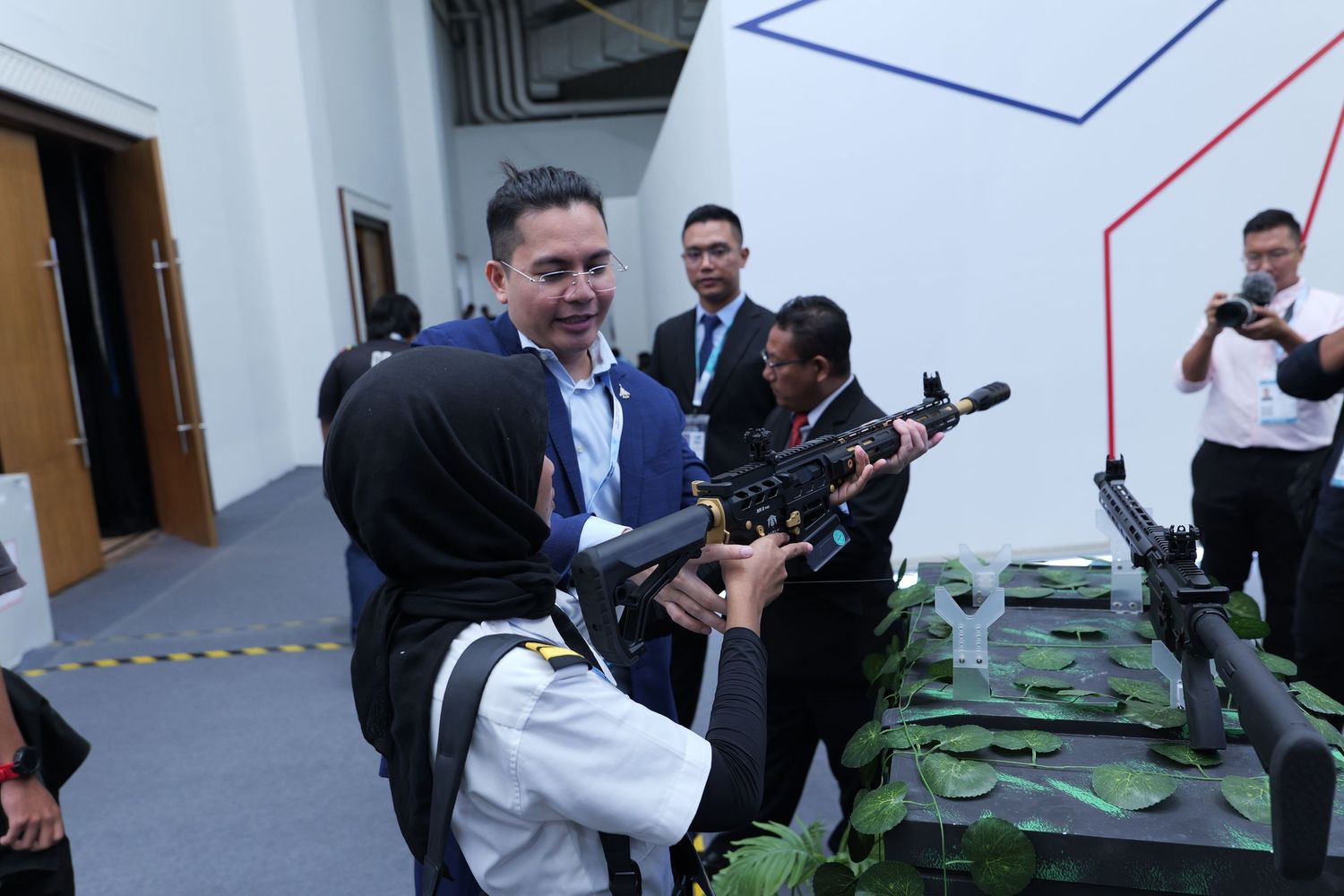 Group of people examining and handling green objects on display tables in conference setting.